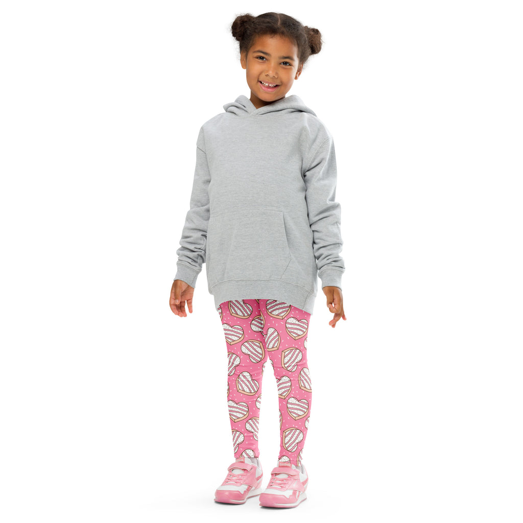 A young girl wearing girls pink heart cookie buttery soft leggings in pink with white hearts and a gray hoodie