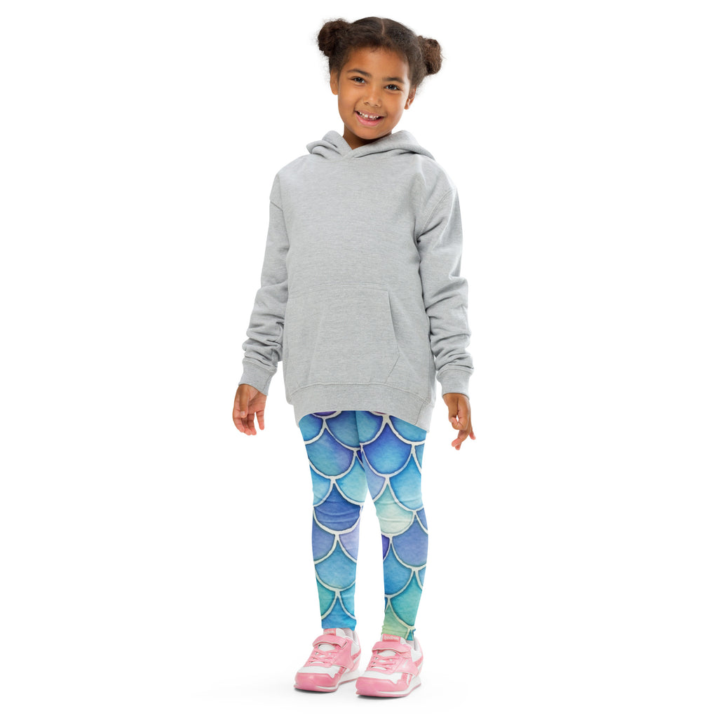 Girl wearing gray hooded sweatshirt with front pocket over blue and teal mermaid watercolor buttery soft leggings