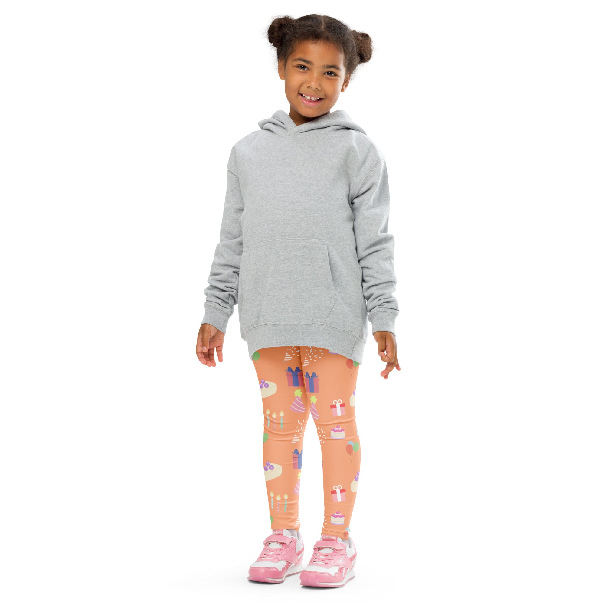 A child wearing kids orange birthday pattern buttery soft peach leggings with gift and cake print and a gray hooded sweatshirt