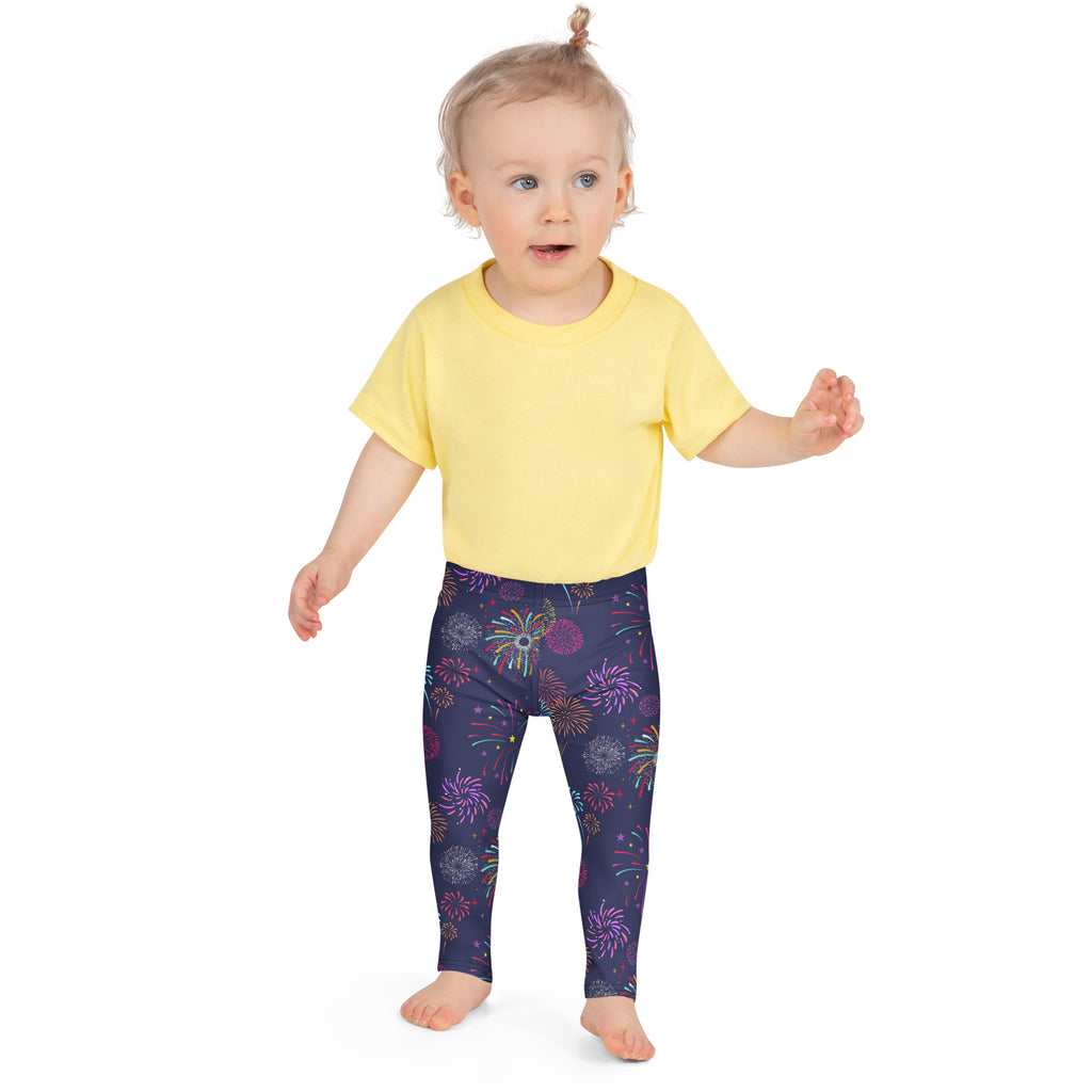 A child wearing girls fireworks buttery soft leggings in navy blue with vibrant purple pink and gold fireworks pattern