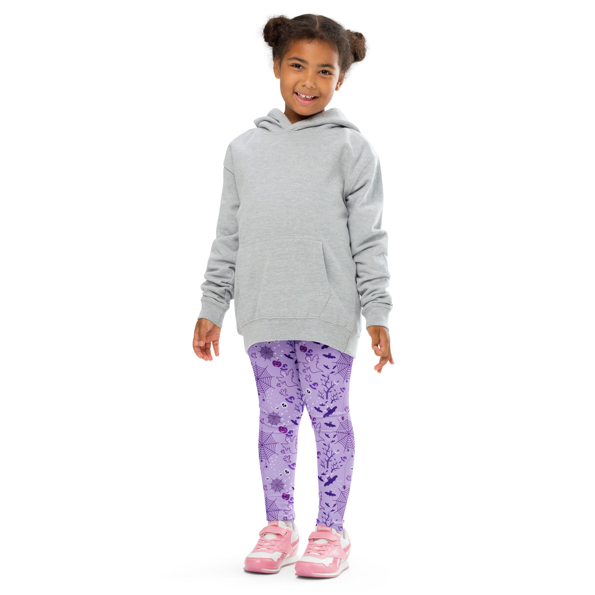 A child wearing kids purple halloween buttery soft leggings with spiderweb and bat patterns paired with a gray hoodie