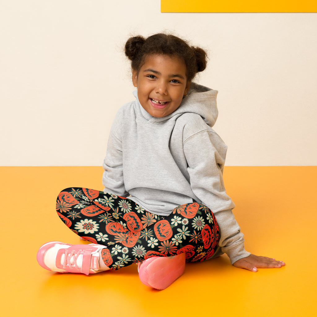 A child wearing kids vintage Halloween pumpkin floral buttery soft black leggings paired with pink sneakers