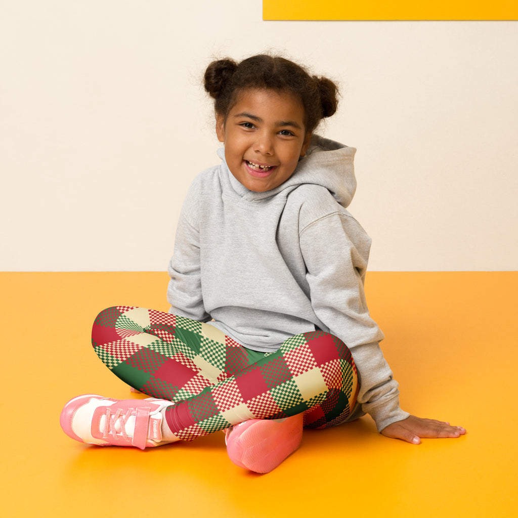 A young girl wearing kids christmas plaid buttery soft red green and beige leggings paired with a gray hoodie
