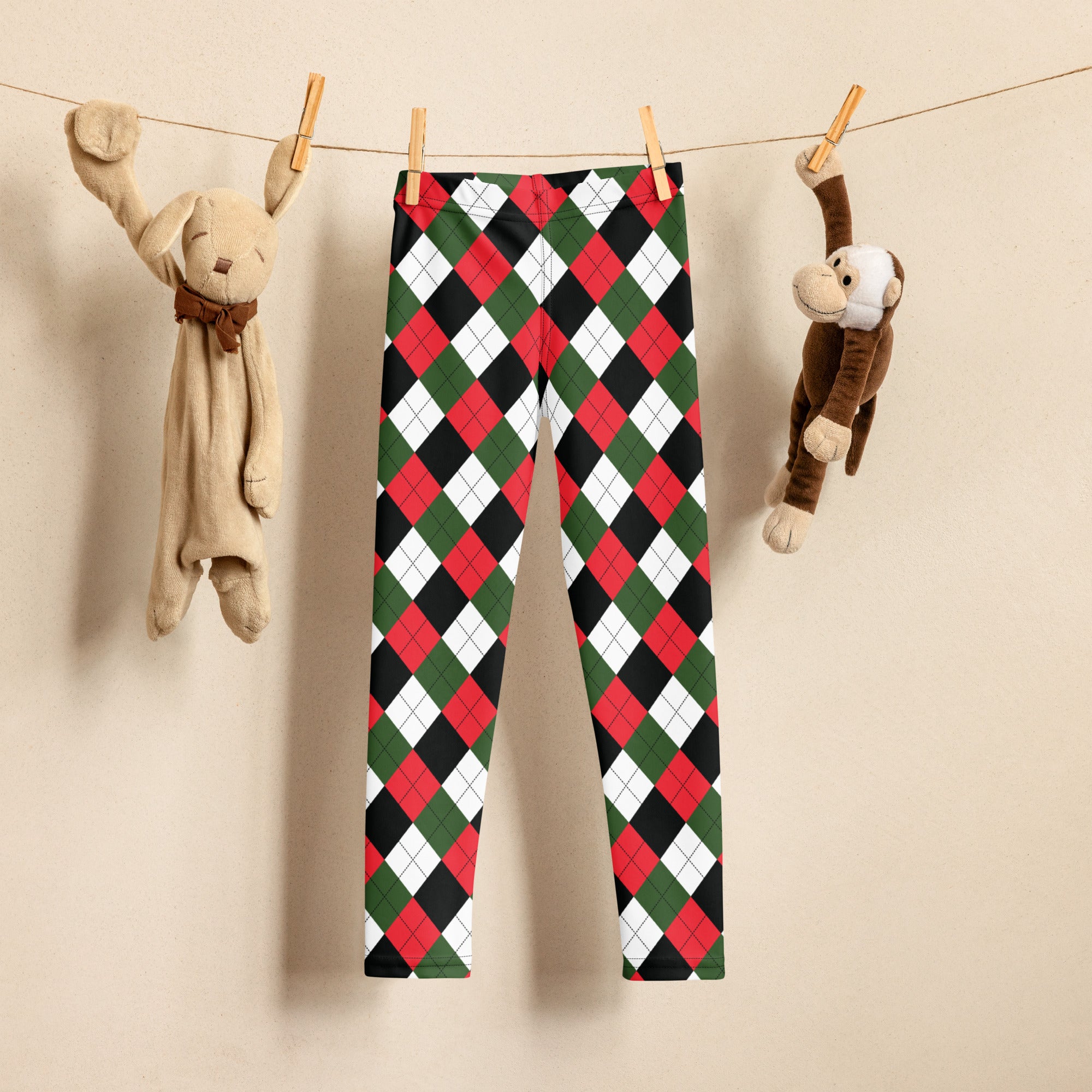 Kids red green and black argyle buttery soft leggings hanging on a clothesline showing front side