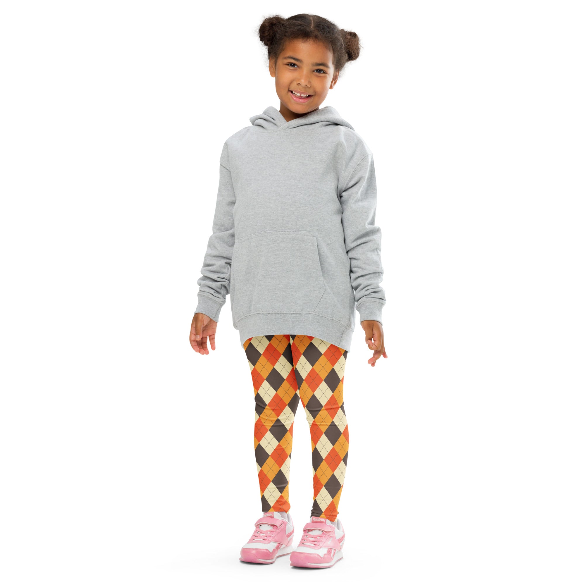 A young girl wearing kids fall argyle buttery soft leggings in orange brown cream with a light gray hooded sweatshirt