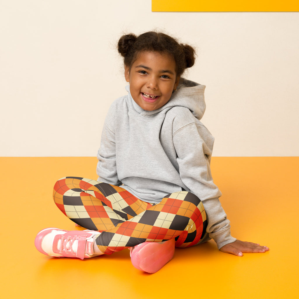 A child wearing kids fall argyle buttery soft leggings with orange black and cream geometric patterns and a gray hoodie