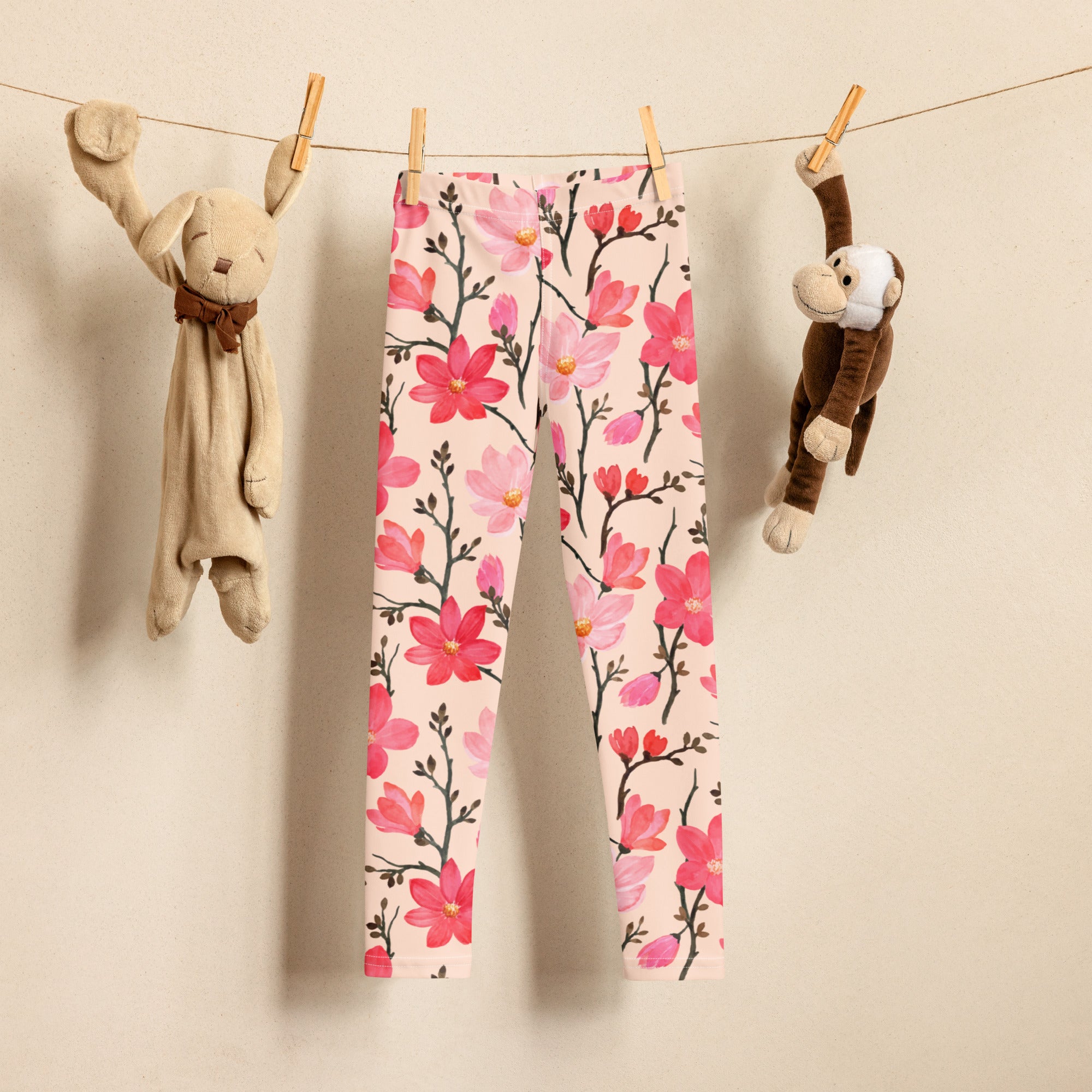 Girls pink buttery soft leggings with floral pattern featuring black stems and yellow centers hanging on clothesline