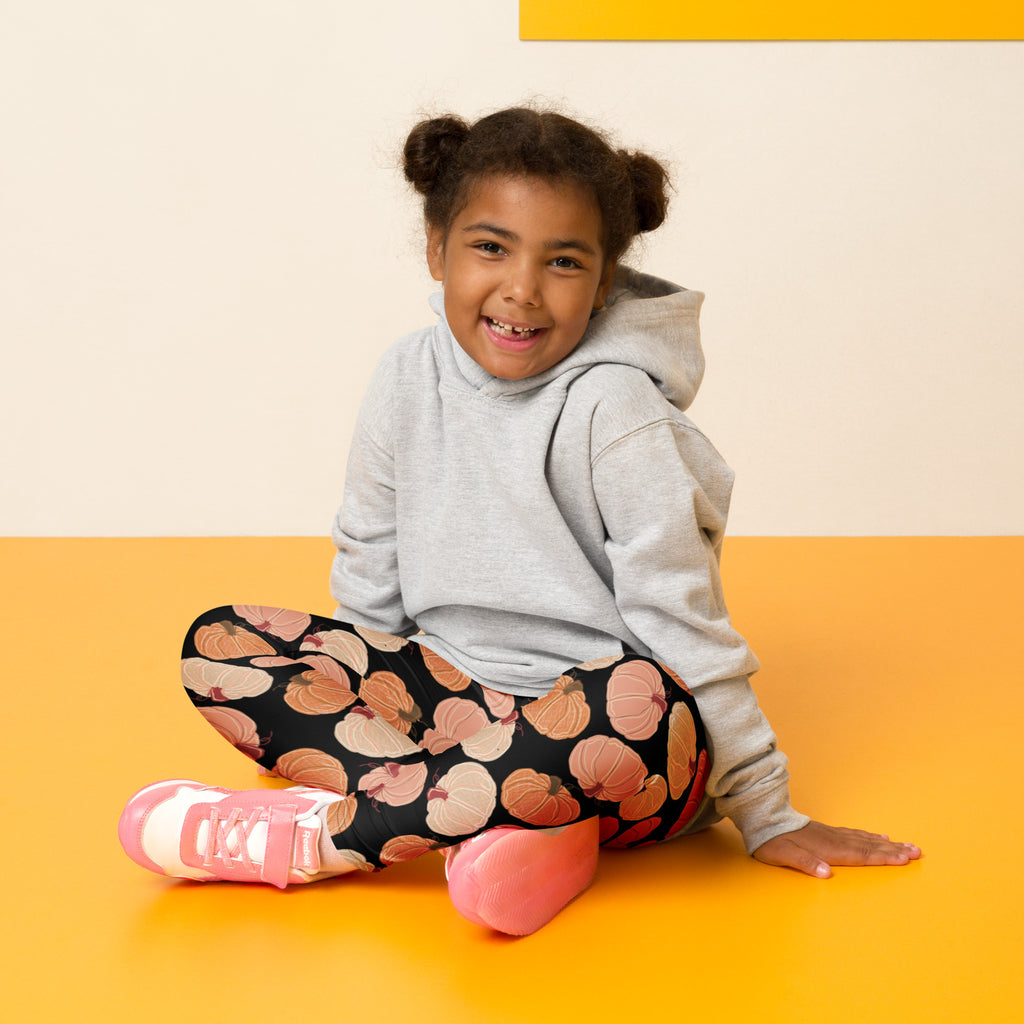 A child wearing kids fall pumpkins buttery soft black leggings with pink pumpkin prints and pink sneakers