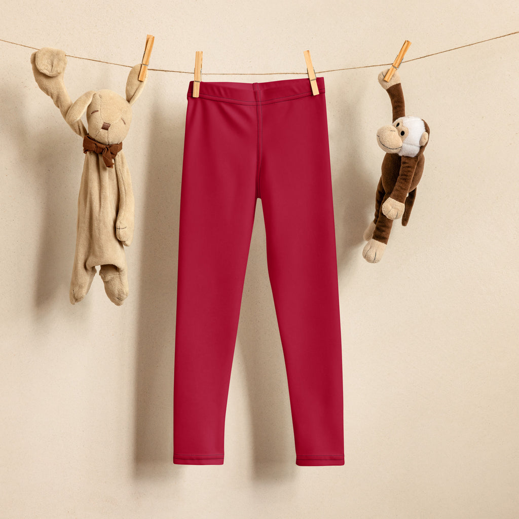 A pair of kids dark red buttery soft leggings hanging on a clothesline showing vibrant color and soft fabric