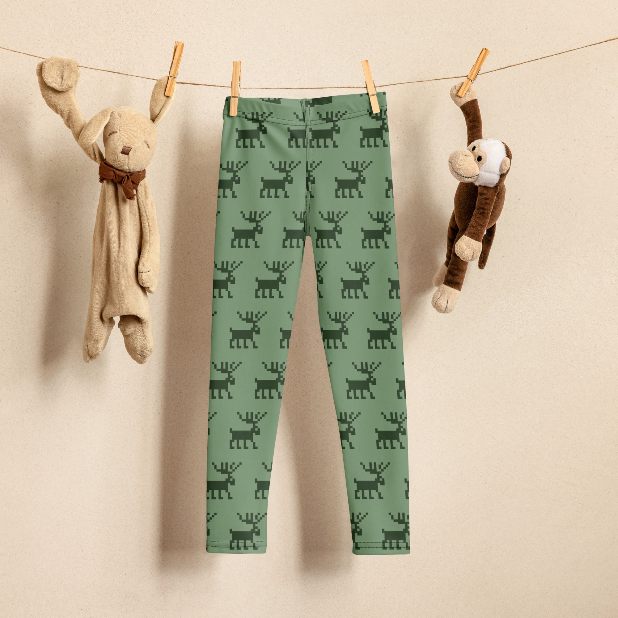 Kids green buttery soft leggings with a dark green pixelated reindeer pattern perfect for Christmas wear