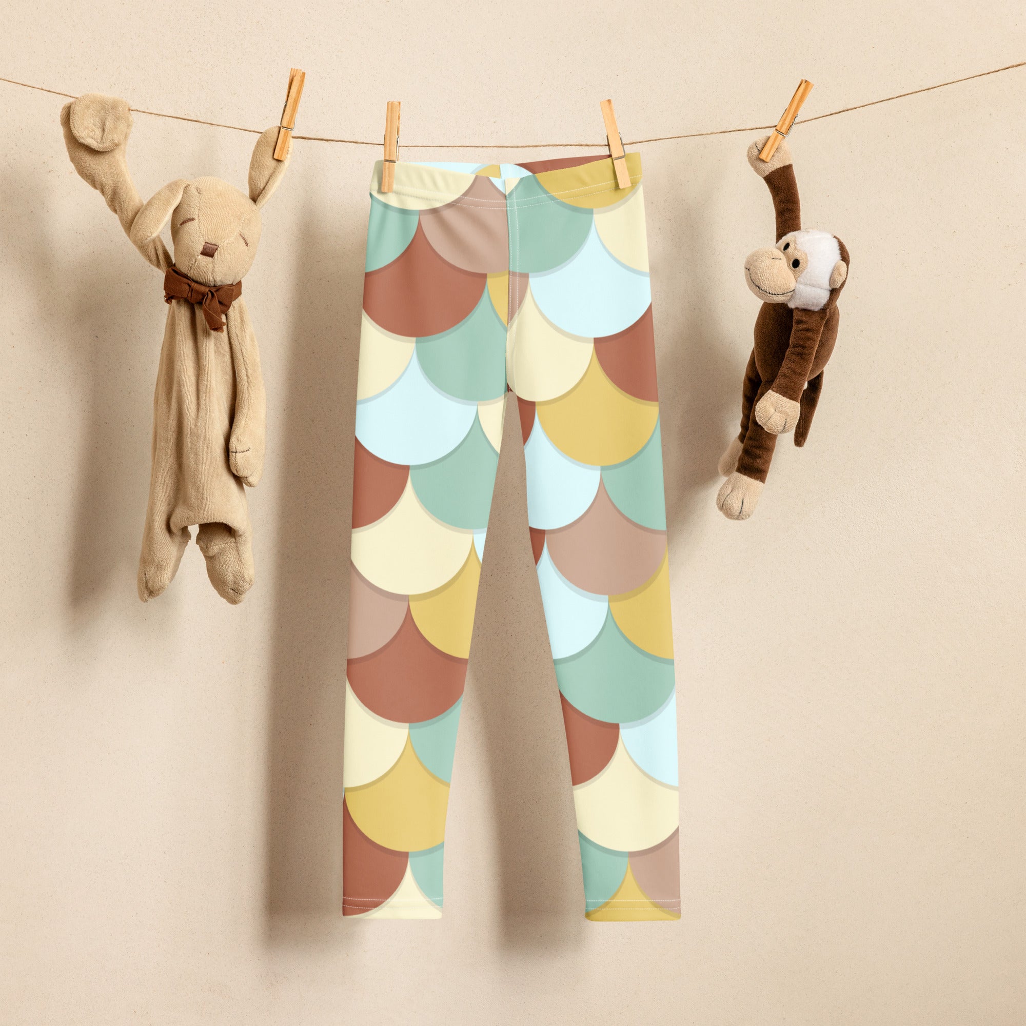 Girls green and brown mermaid buttery soft leggings with colorful pastel scalloped pattern hanging on a clothesline