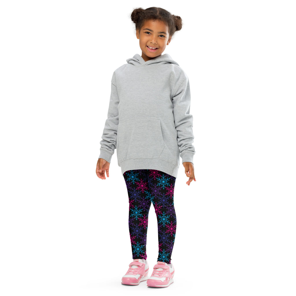 A child wearing girls neon snowflake buttery soft leggings with multicolored snowflake patterns and pink sneakers