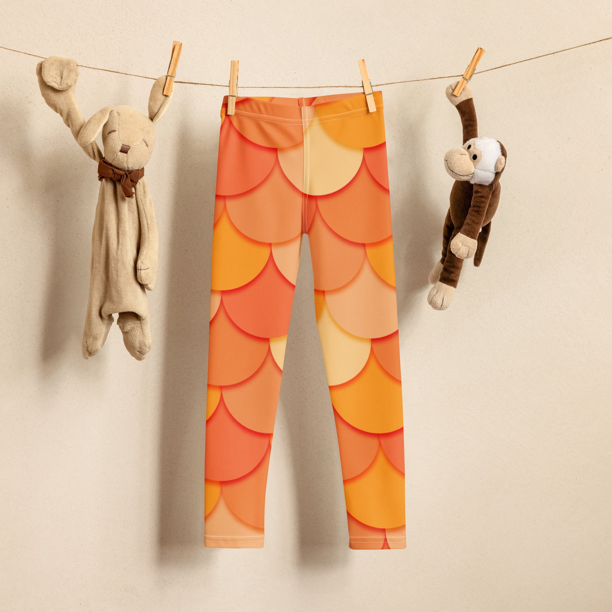 Girls orange mermaid buttery soft leggings with orange and yellow fish-scale pattern hanging on a clothesline