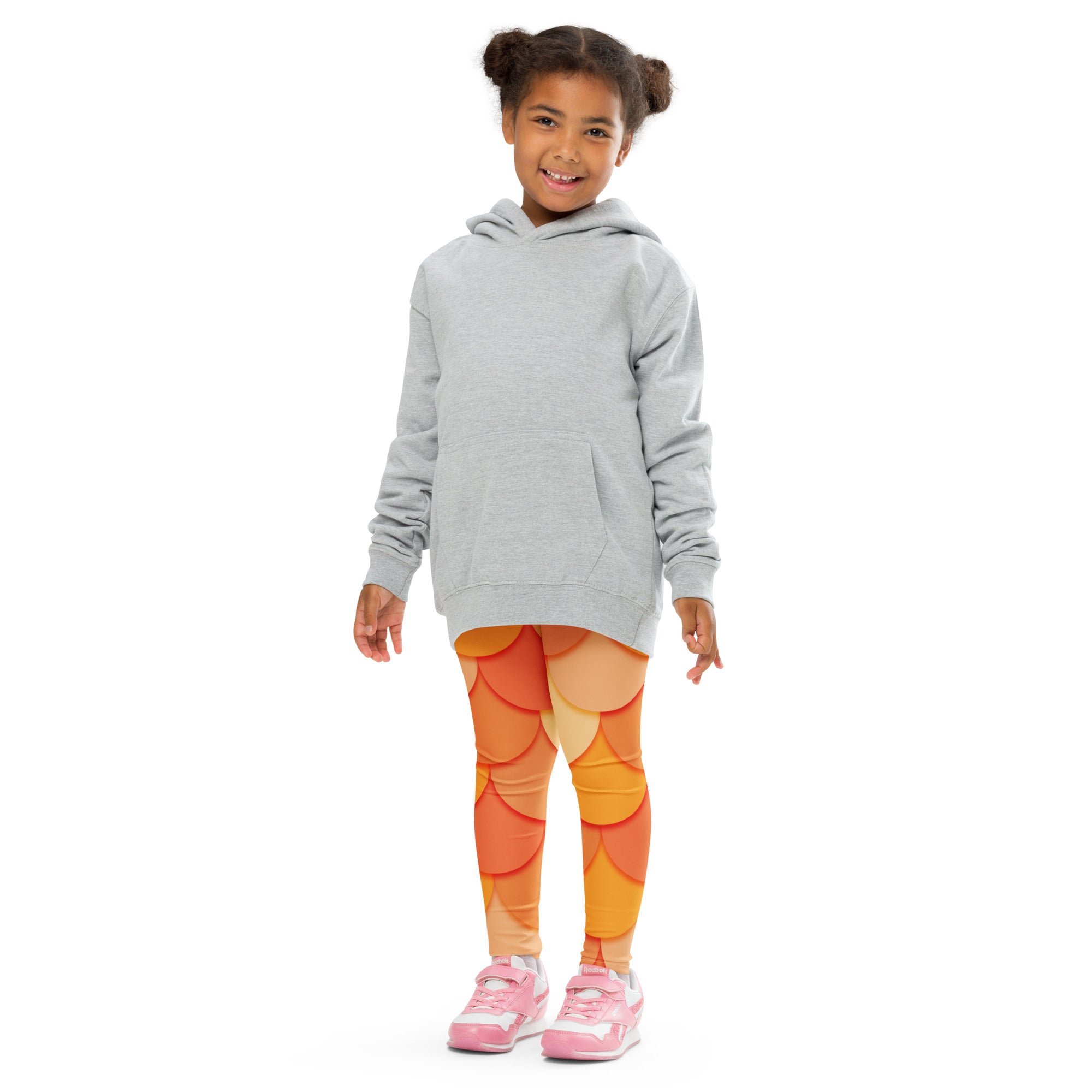A child wearing girls orange mermaid buttery soft leggings with vibrant scale pattern and a light gray hooded sweatshirt