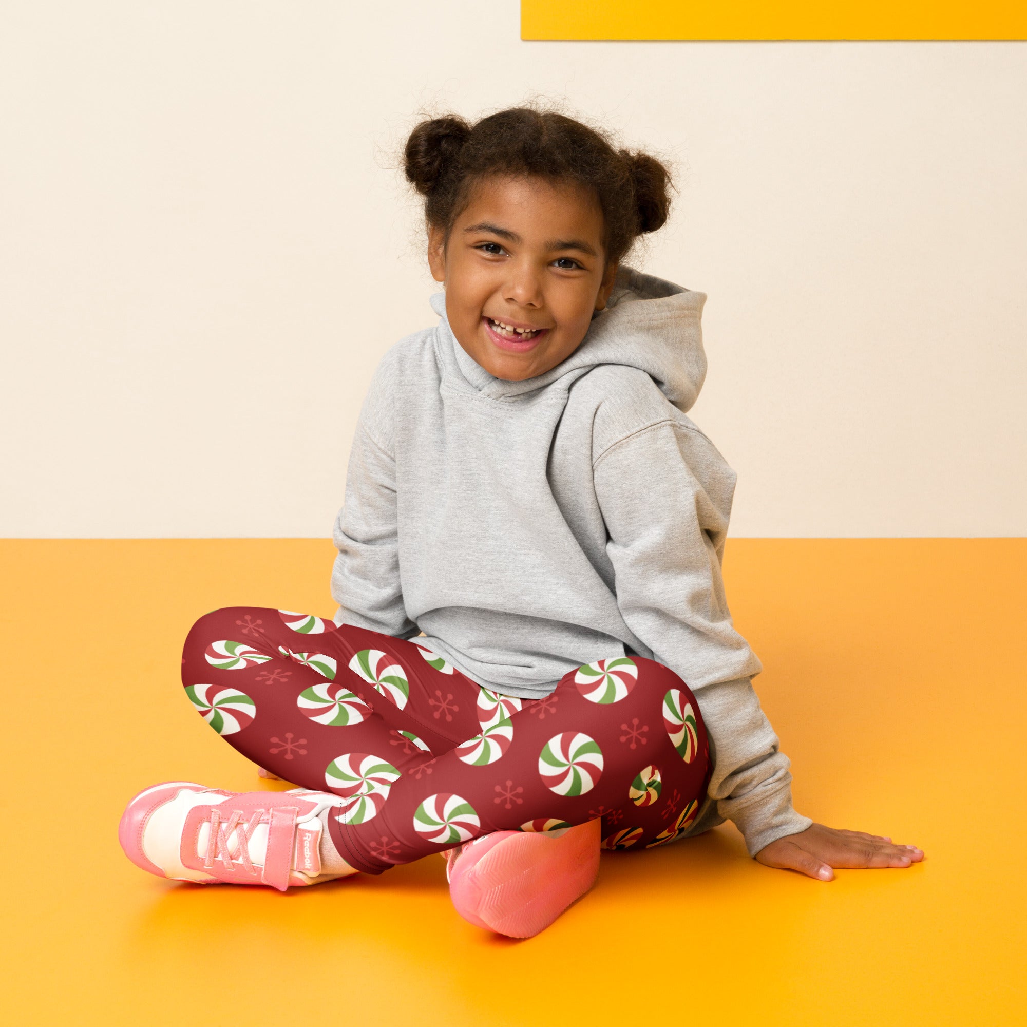 A child wearing kids christmas peppermint buttery soft red leggings with green and white peppermint candy pattern