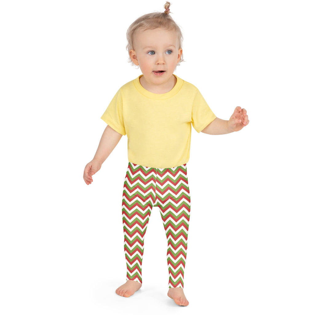 A child wearing kids christmas chevron buttery soft leggings with red green and white zigzag patterns and a yellow shirt