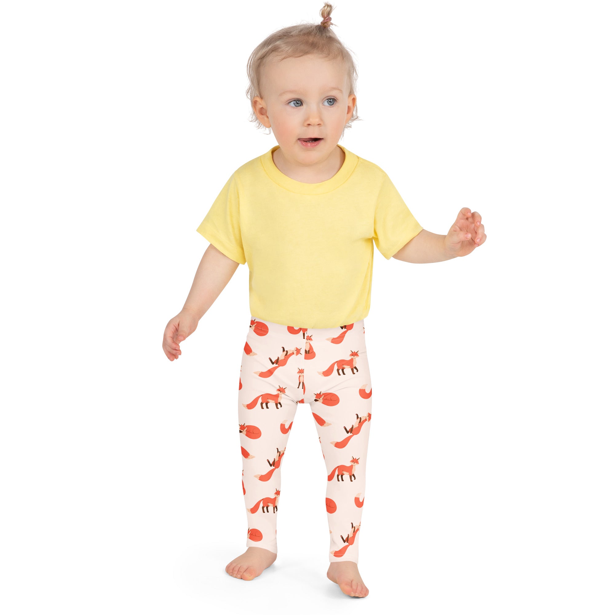A child wearing kids fox print buttery soft cream leggings with orange fox pattern and a yellow short sleeve t-shirt