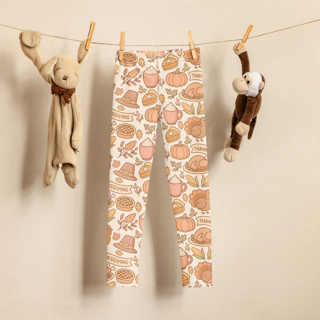 Kids thanksgiving buttery soft leggings with cream base and orange brown pink pumpkins pies turkeys hats and leaves illustrations