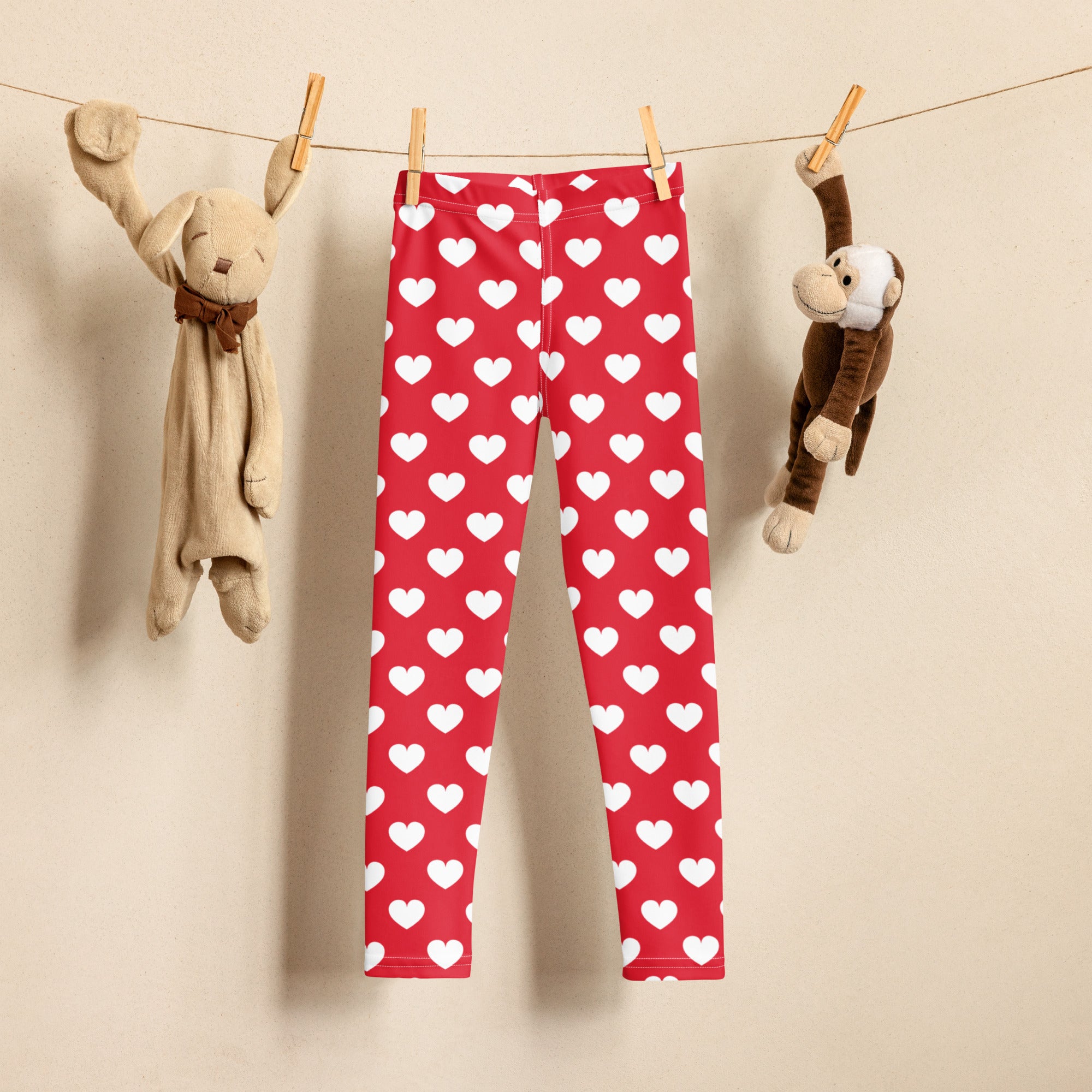 Girls red heart buttery soft leggings with white heart pattern hanging on a clothesline