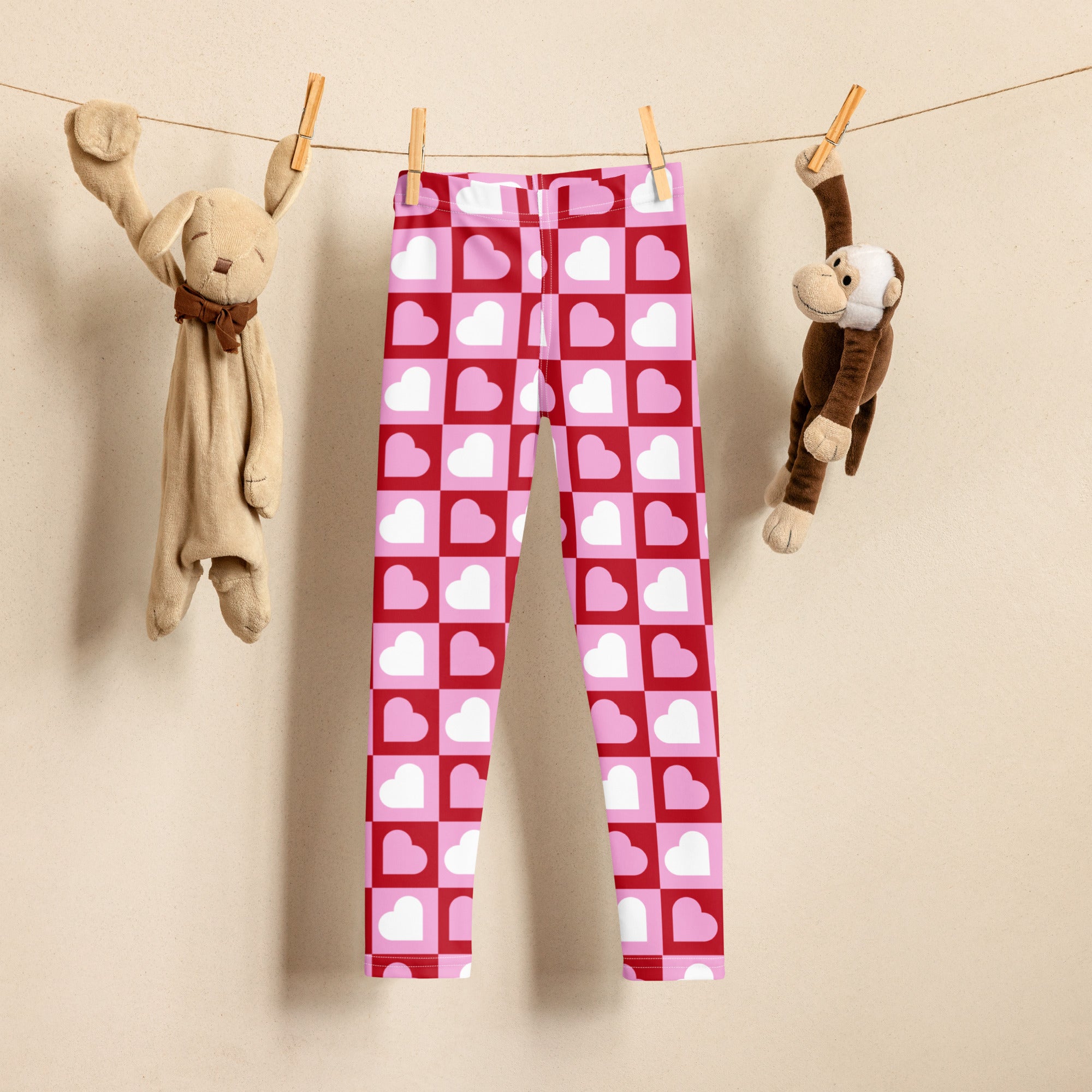 Girls pink checkered heart buttery soft leggings in pink and red heart patterns hanging on a clothesline