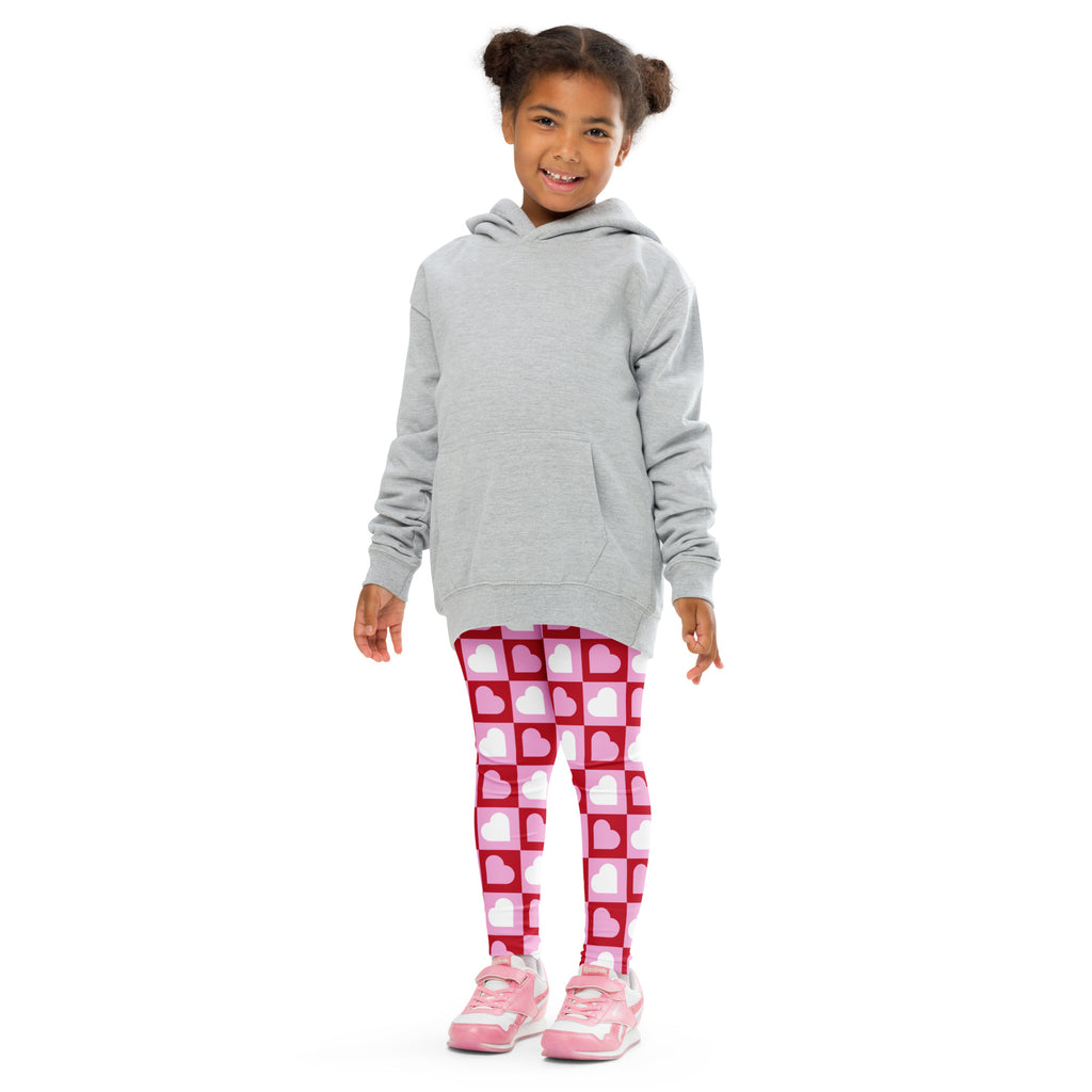 A child wearing girls pink checkered heart buttery soft leggings with red and white heart patterns and a gray hoodie