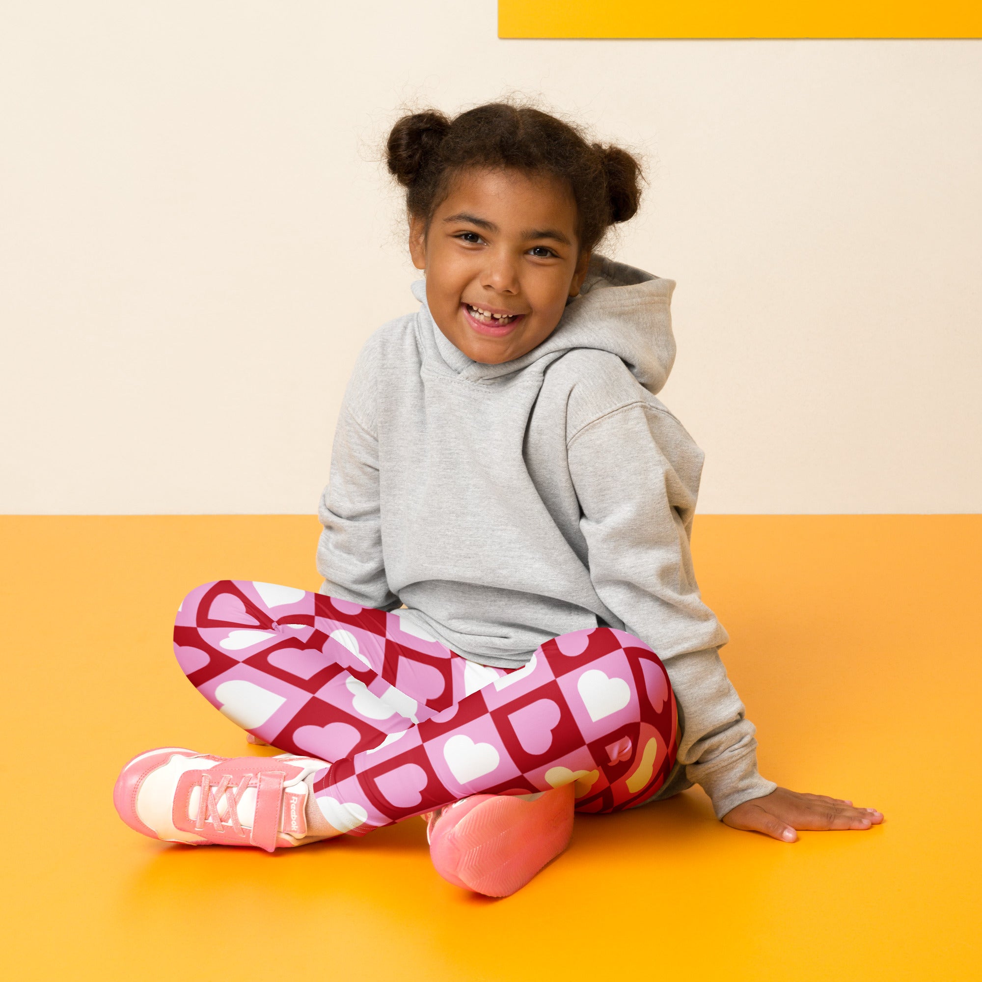 A child wearing girls pink checkered heart buttery soft leggings in pink with gray hoodie