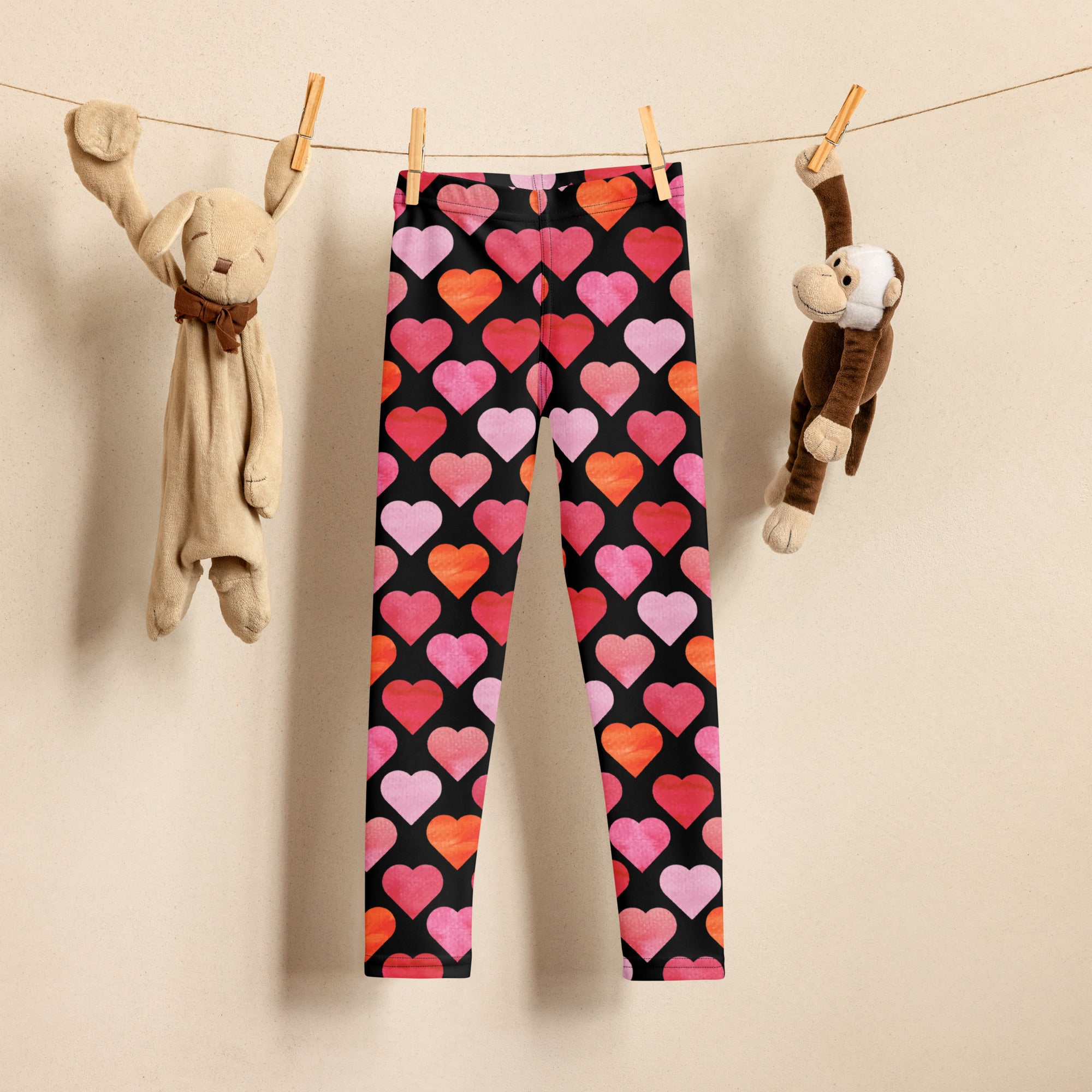 Girls black heart buttery soft leggings featuring vibrant pink orange and red heart patterns on black fabric