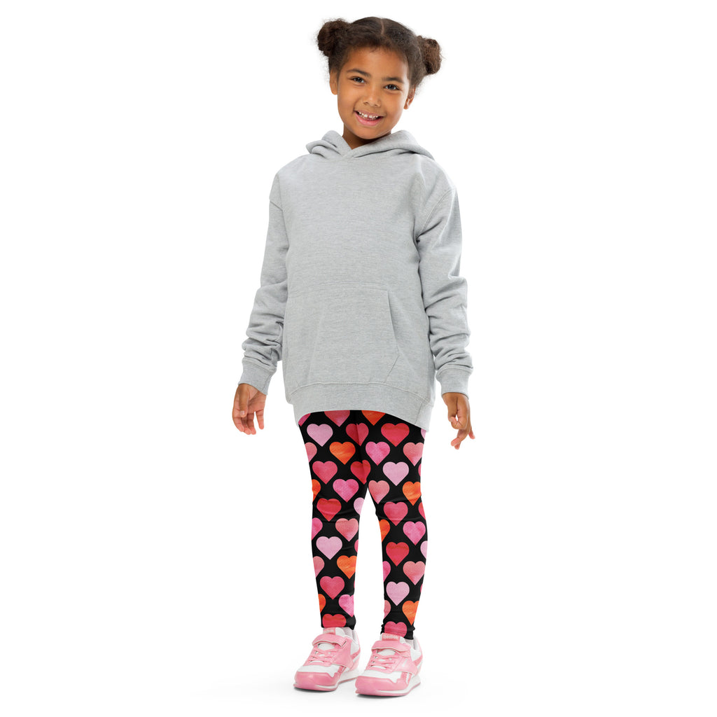 A child wearing girls black heart buttery soft leggings in black with colorful pink and orange hearts and a gray hoodie