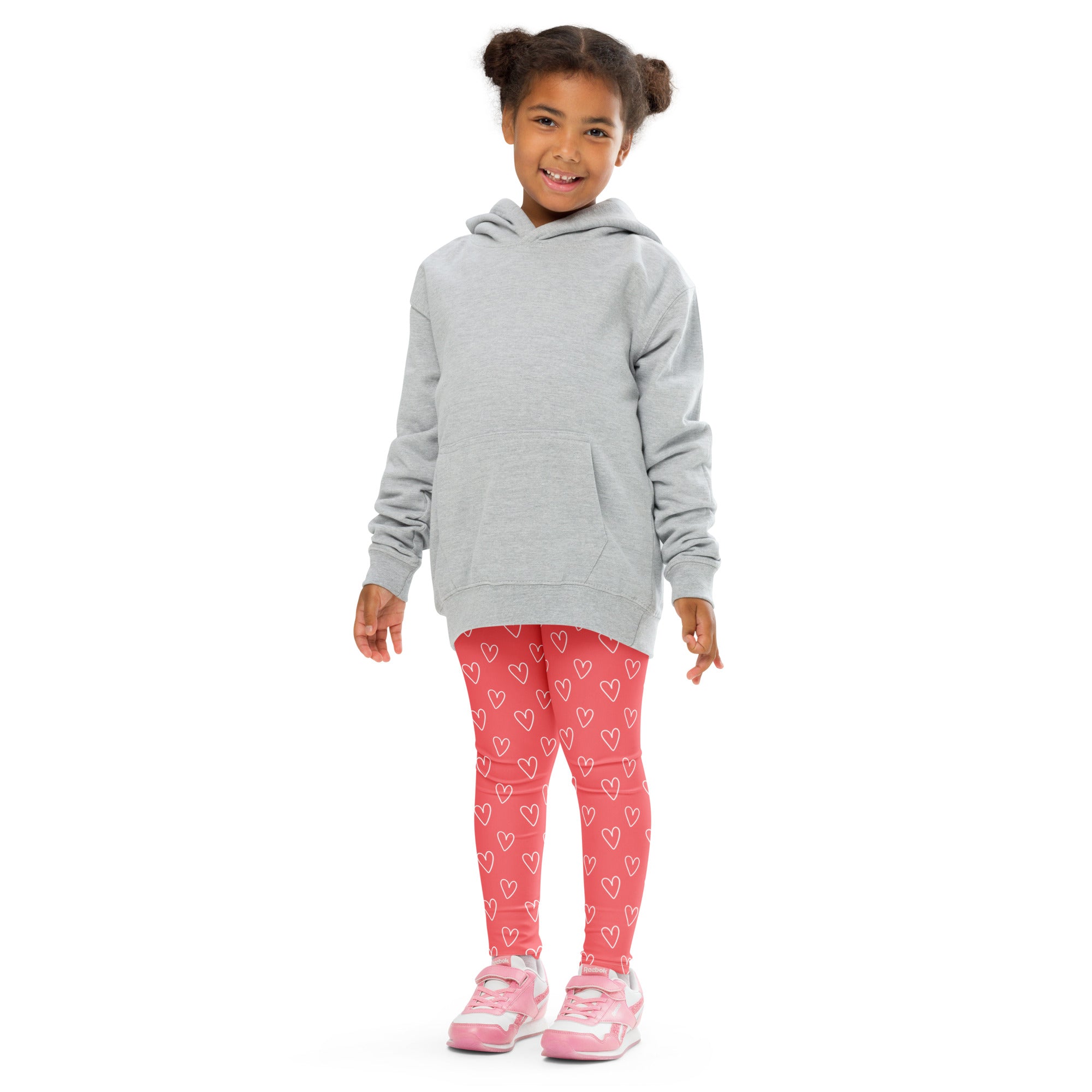 Girl wearing pink heart outline buttery soft leggings paired with a gray hooded sweatshirt with front pocket