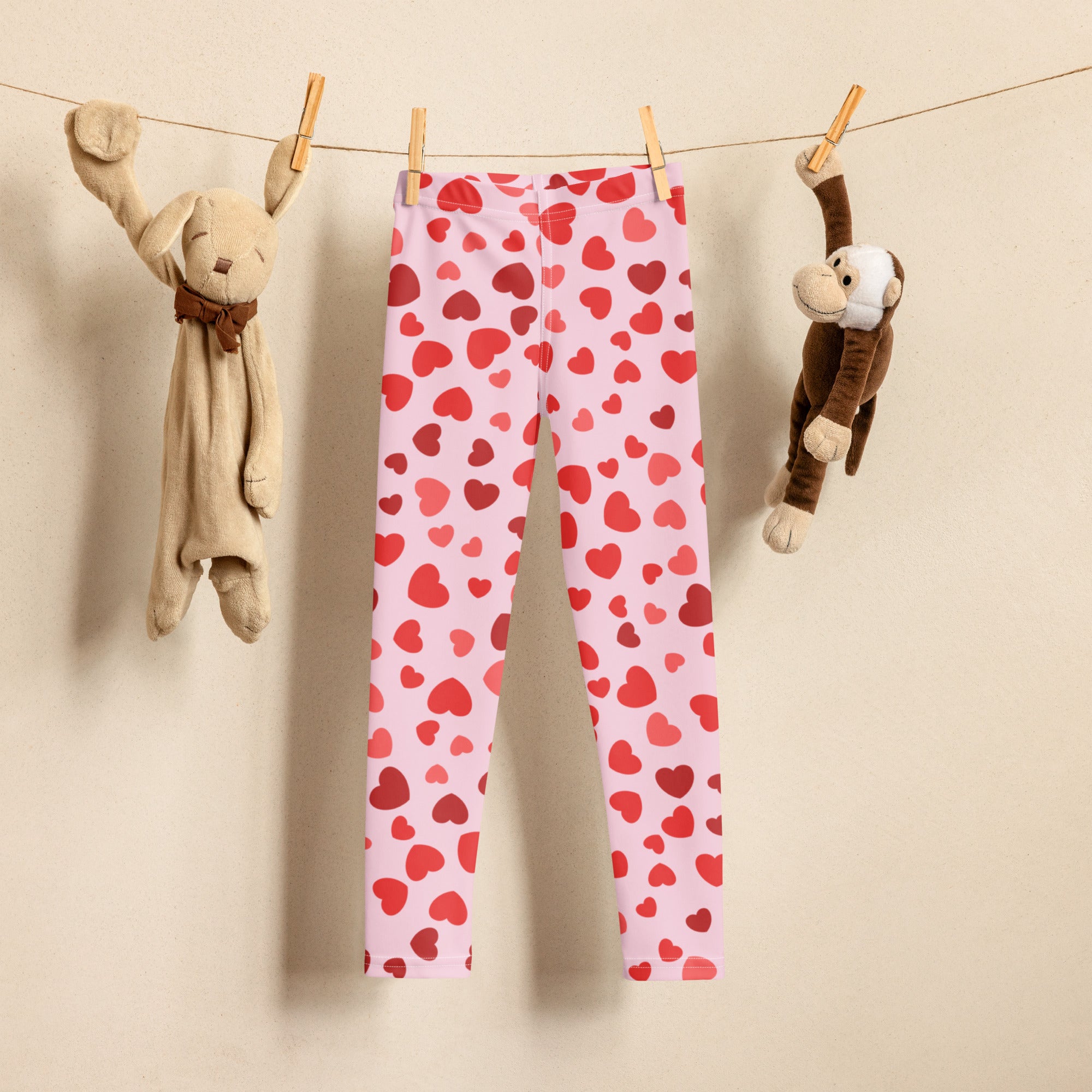 Girls valentine’s day pink buttery soft leggings with red heart pattern hanging on a clothesline
