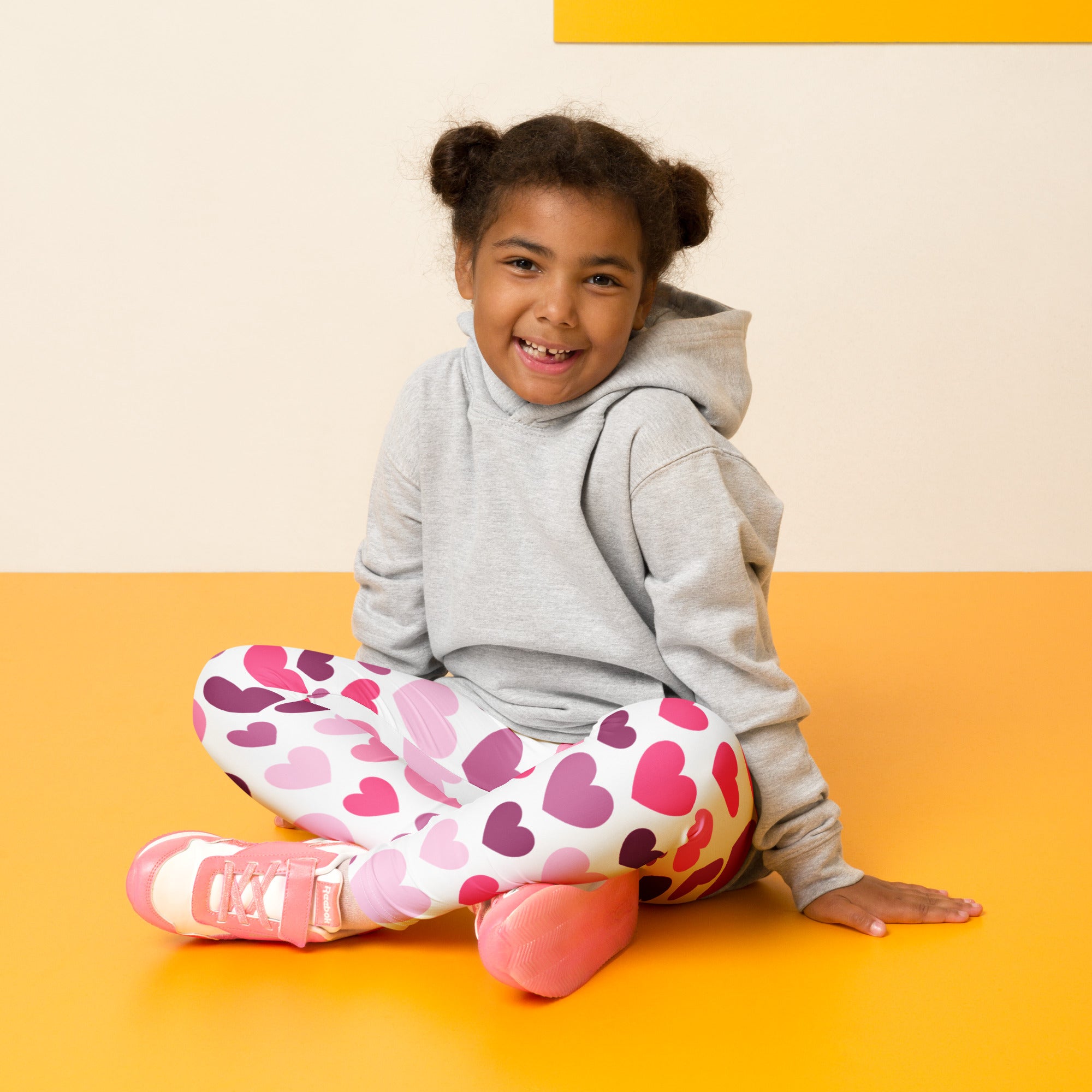A child wearing girls purple and pink hearts buttery soft leggings with gray hoodie and pink sneakers