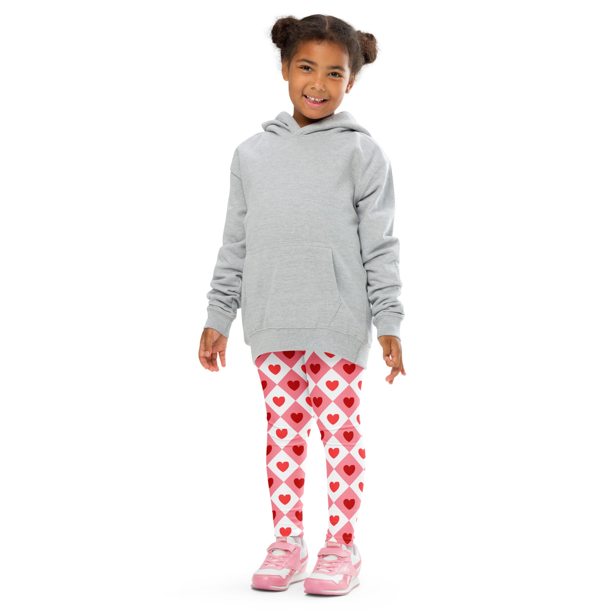 A child wearing girls pink argyle heart buttery soft leggings paired with a light gray hooded sweatshirt
