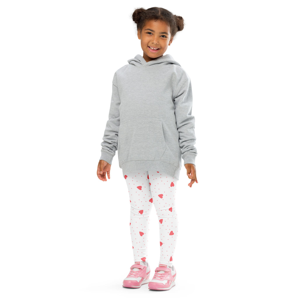 A child wearing buttery soft white girls scattered heart leggings with pink hearts and a light gray hooded sweatshirt