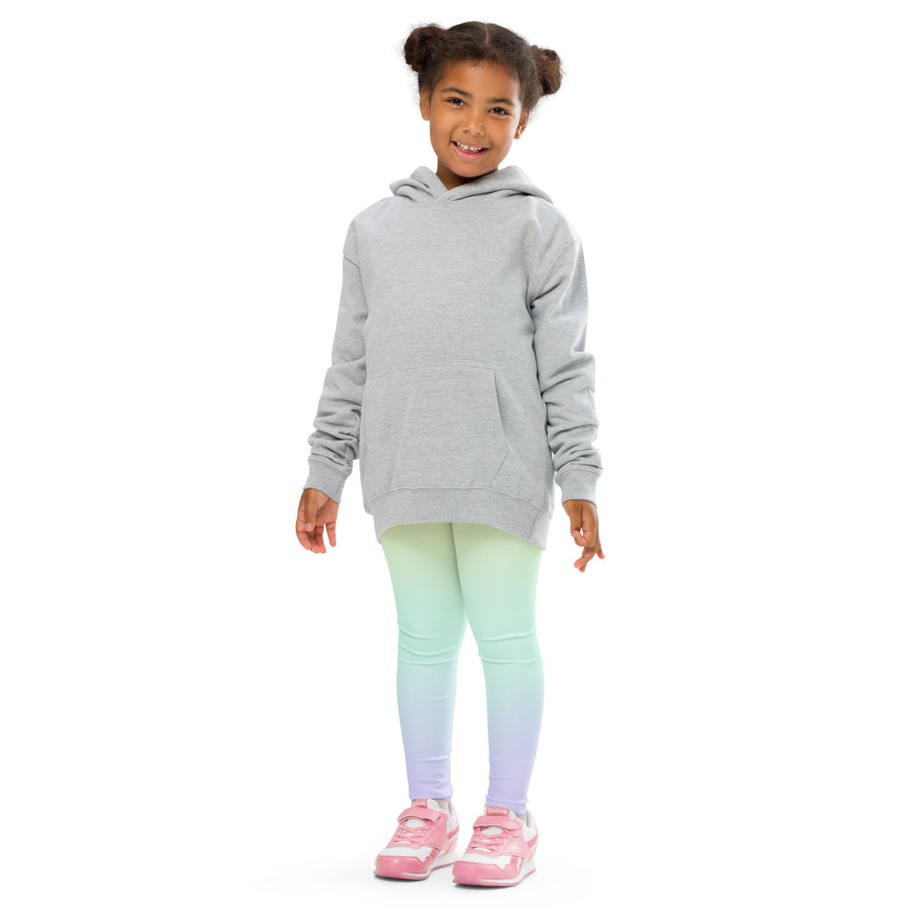 A child wearing girls pastel rainbow buttery soft leggings in mint green to lavender gradient and a light gray hooded sweatshirt