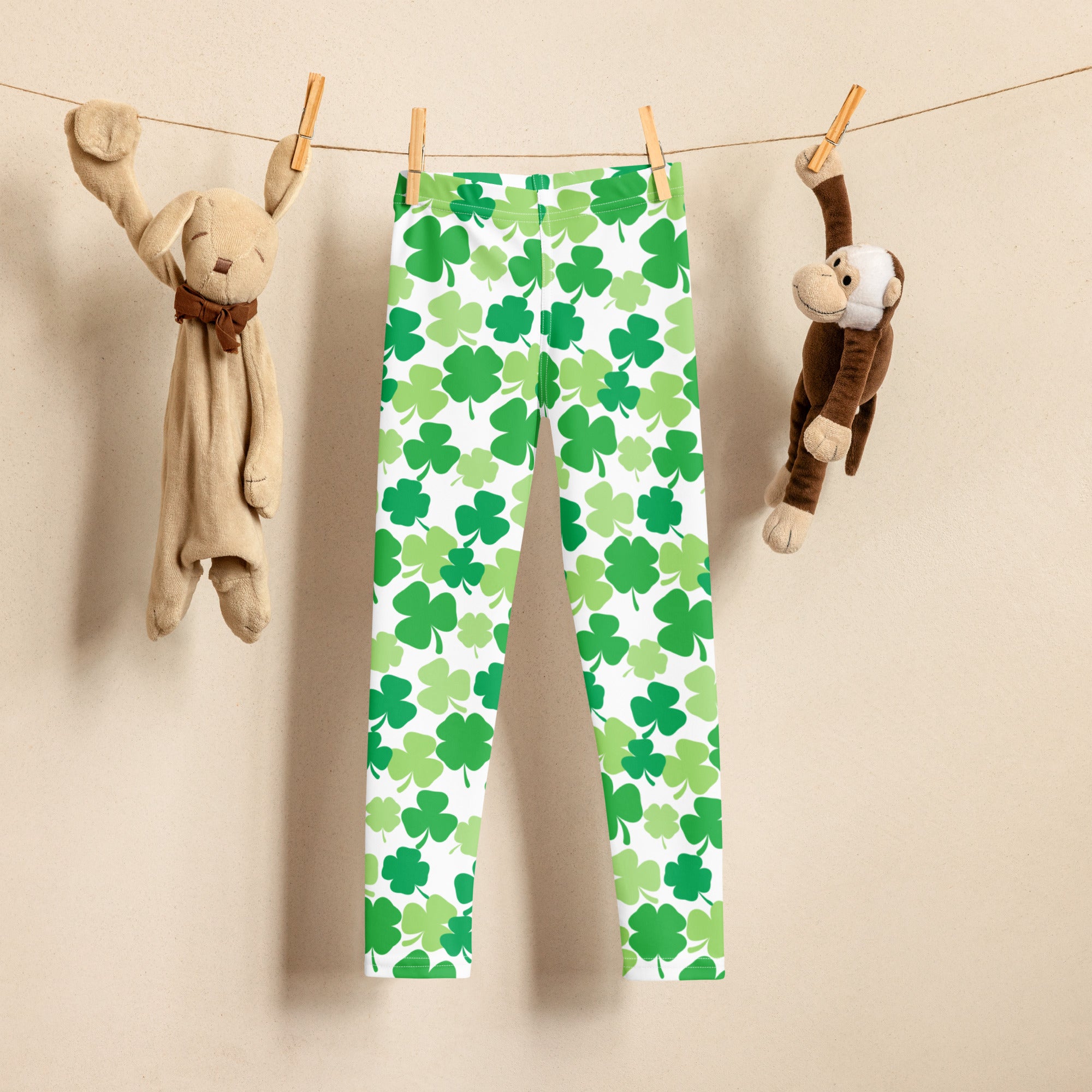 Girls green shamrock buttery soft leggings hanging on a clothesline showing soft fabric and festive pattern