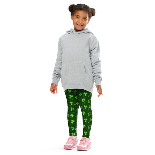 A child wearing green lucky clover buttery soft leggings with bright shamrock patterns and a light gray hooded sweatshirt