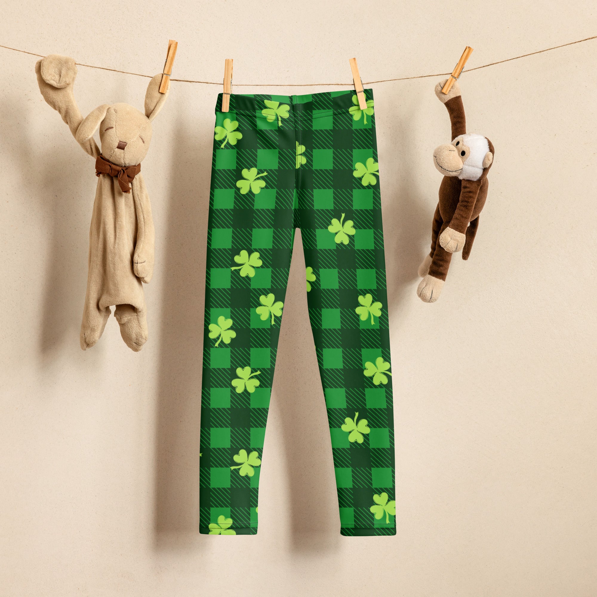 Girls green plaid shamrock buttery soft leggings in green and lime green hanging on a clothesline