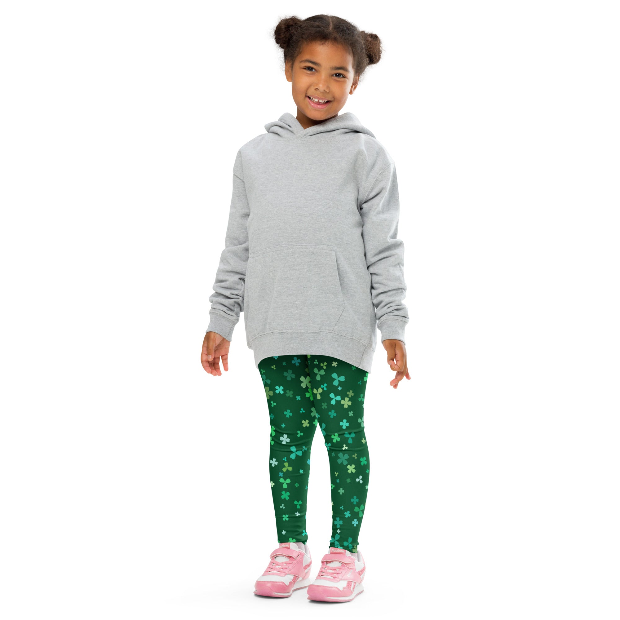 A child wearing girls teal and green shamrock buttery soft leggings with a light gray hooded sweatshirt