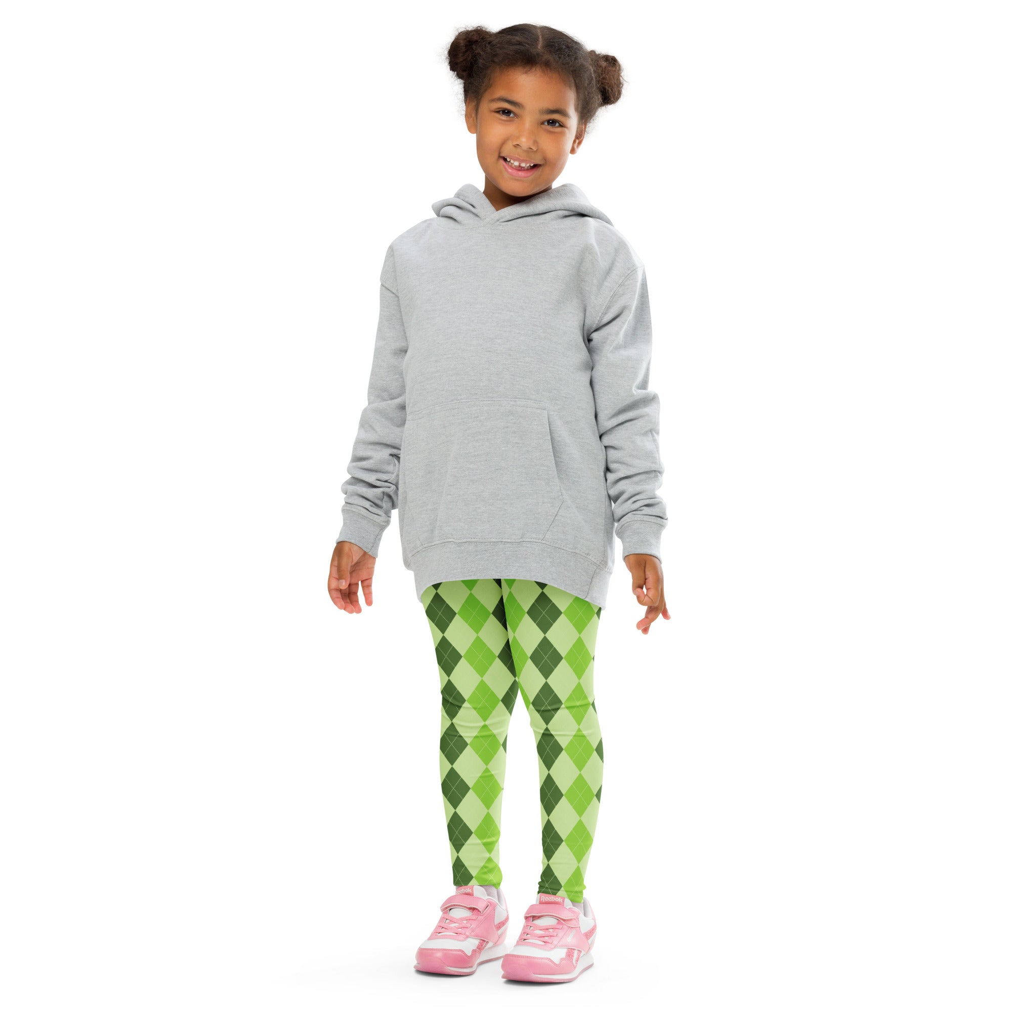 A young girl wearing girls light green argyle buttery soft leggings with a light gray hooded sweatshirt and pink sneakers
