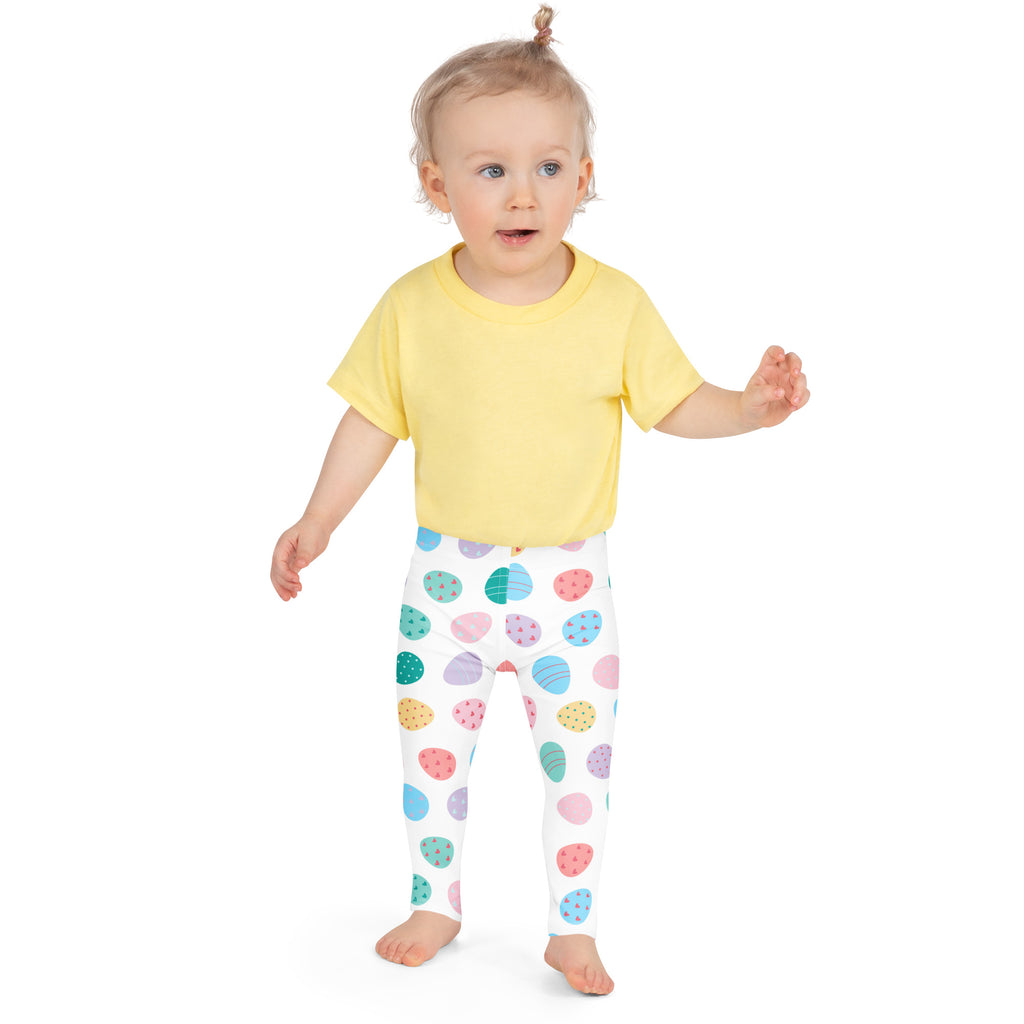 A child wearing yellow t-shirt and white girls pastel Easter egg buttery soft leggings with colorful patterns