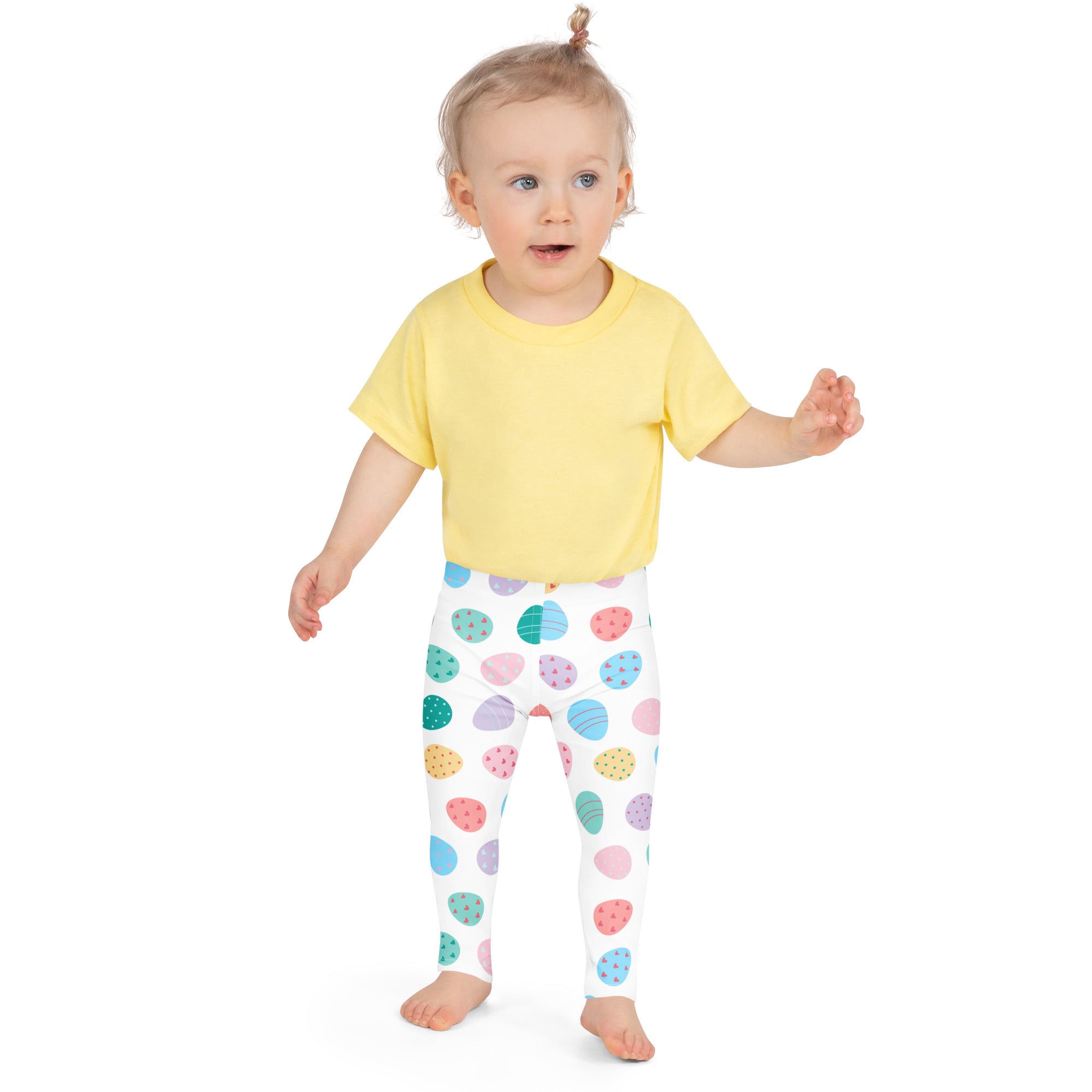 A child wearing yellow t-shirt and white girls pastel Easter egg buttery soft leggings with colorful patterns