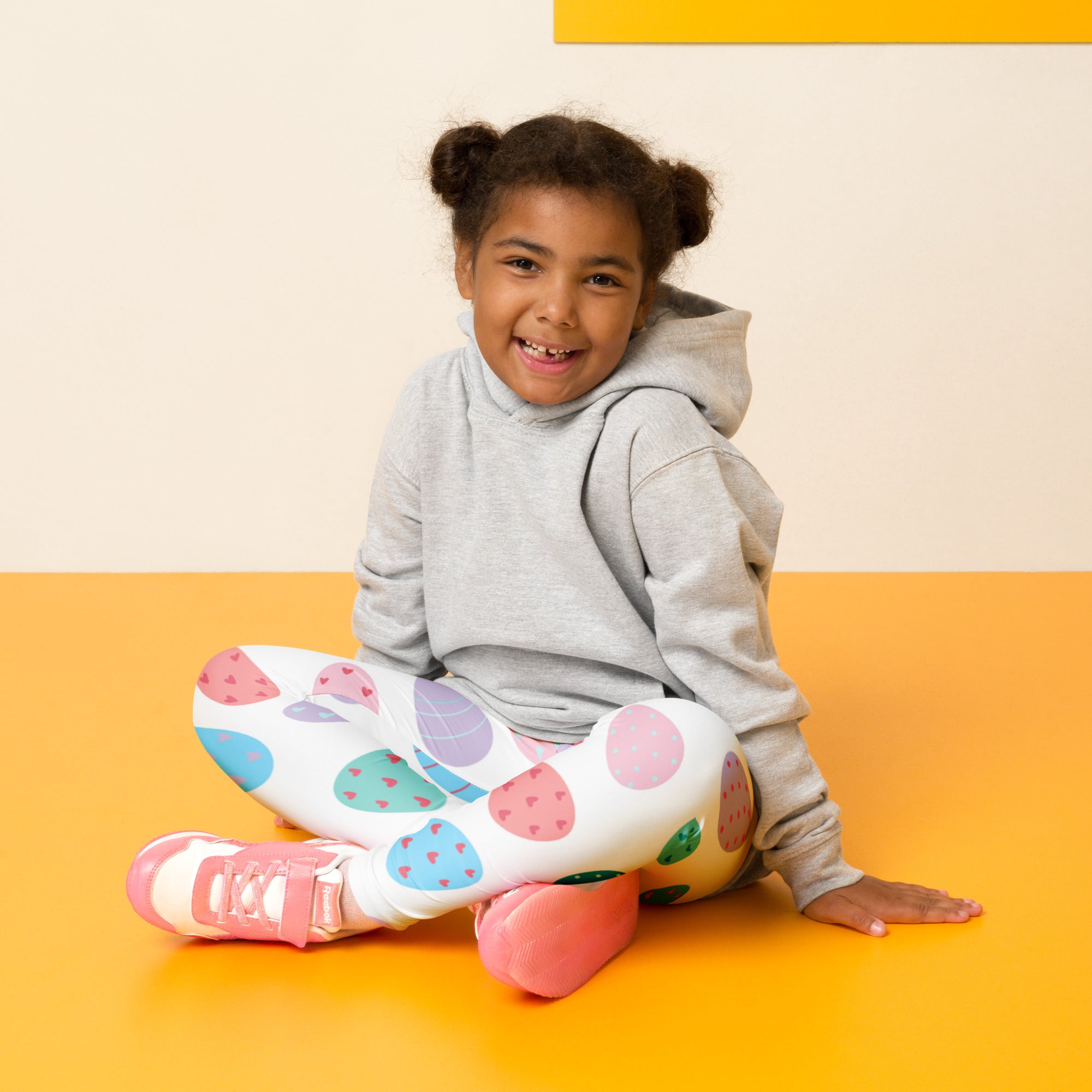 A child wearing gray hoodie and girls pastel Easter egg buttery soft leggings with colorful polka dots and pink shoes