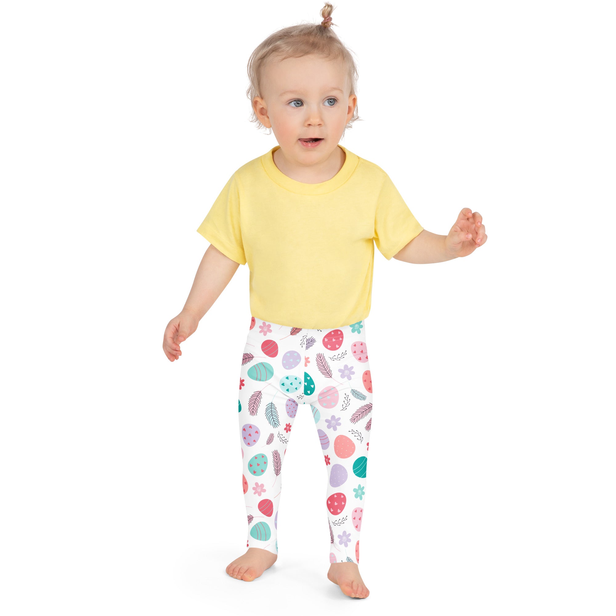 A child wearing buttery soft kids floral Easter egg leggings in white with colorful patterns and a yellow t-shirt