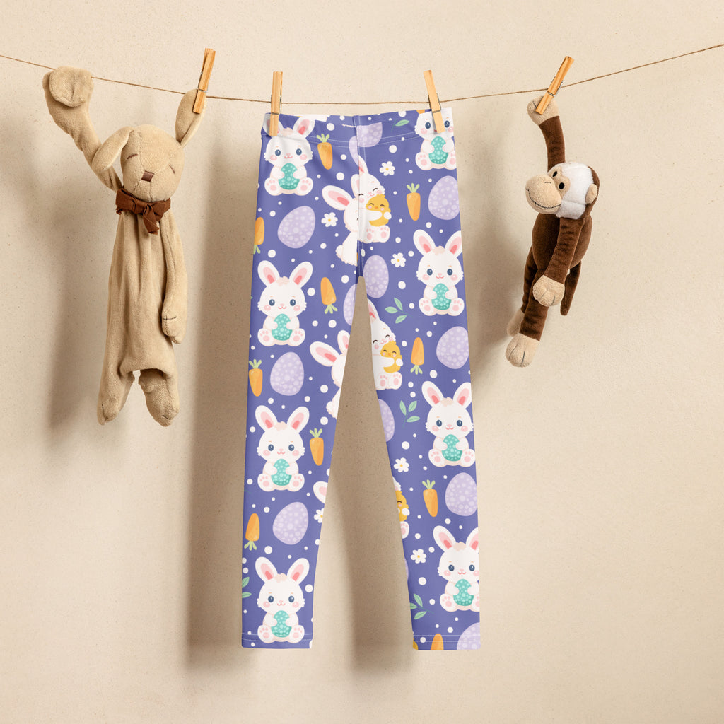 Girls purple buttery soft leggings with playful white bunnies holding green eggs, orange carrots, and purple easter eggs on light background