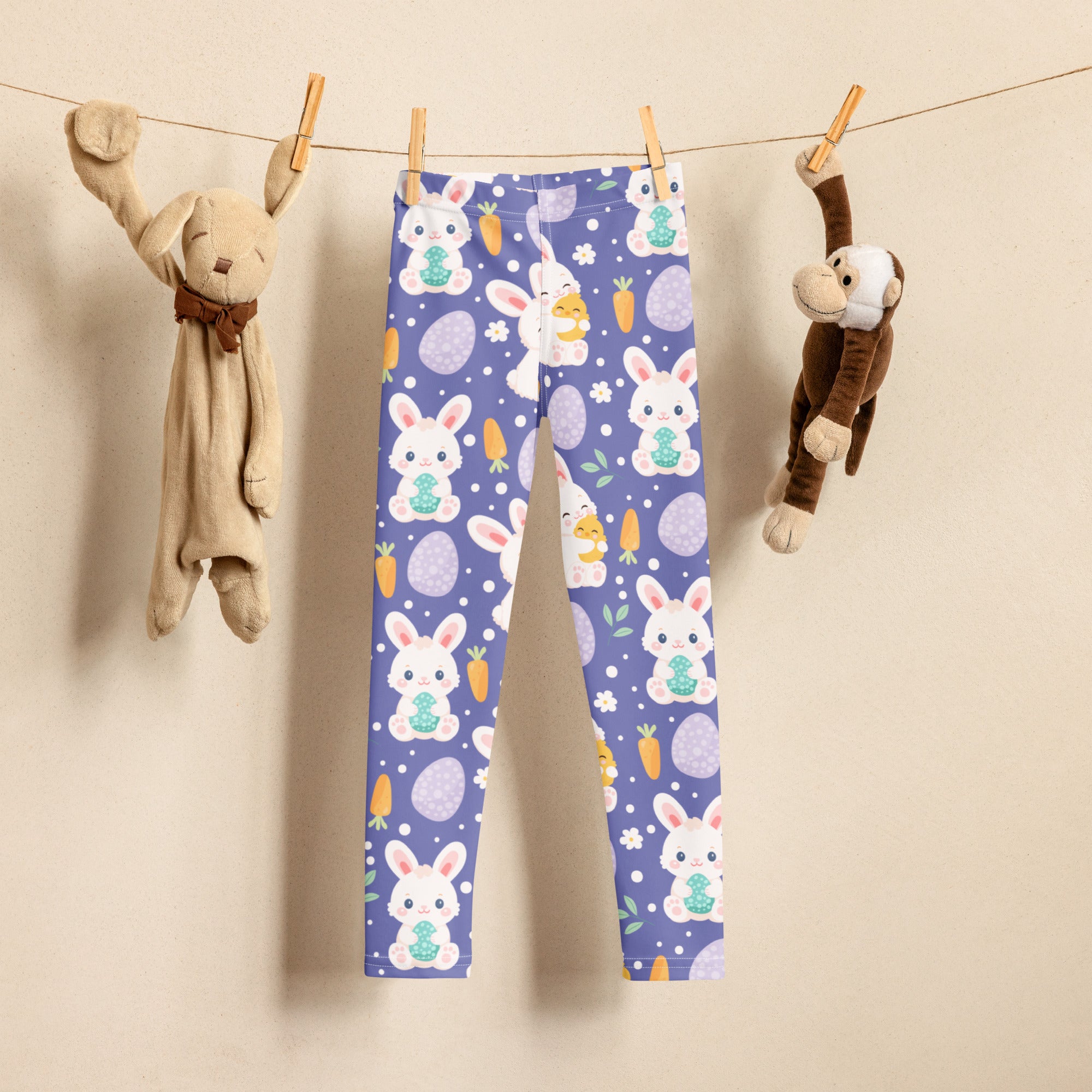 Girls purple buttery soft leggings with playful white bunnies holding green eggs, orange carrots, and purple easter eggs on light background