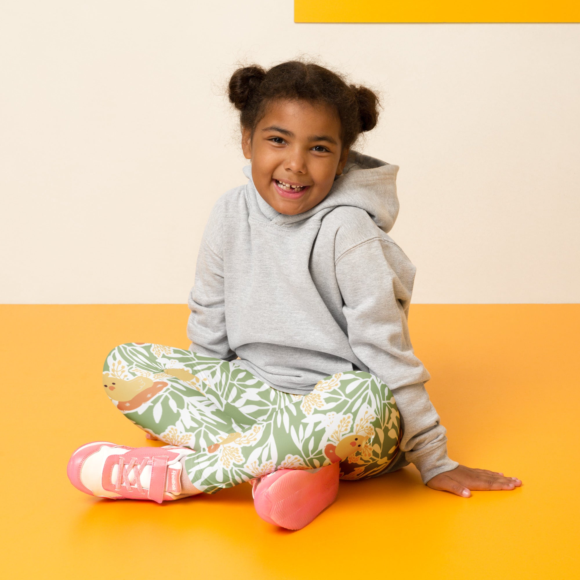A child wearing girls sage green floral buttery soft leggings paired with a gray hoodie and pink shoes