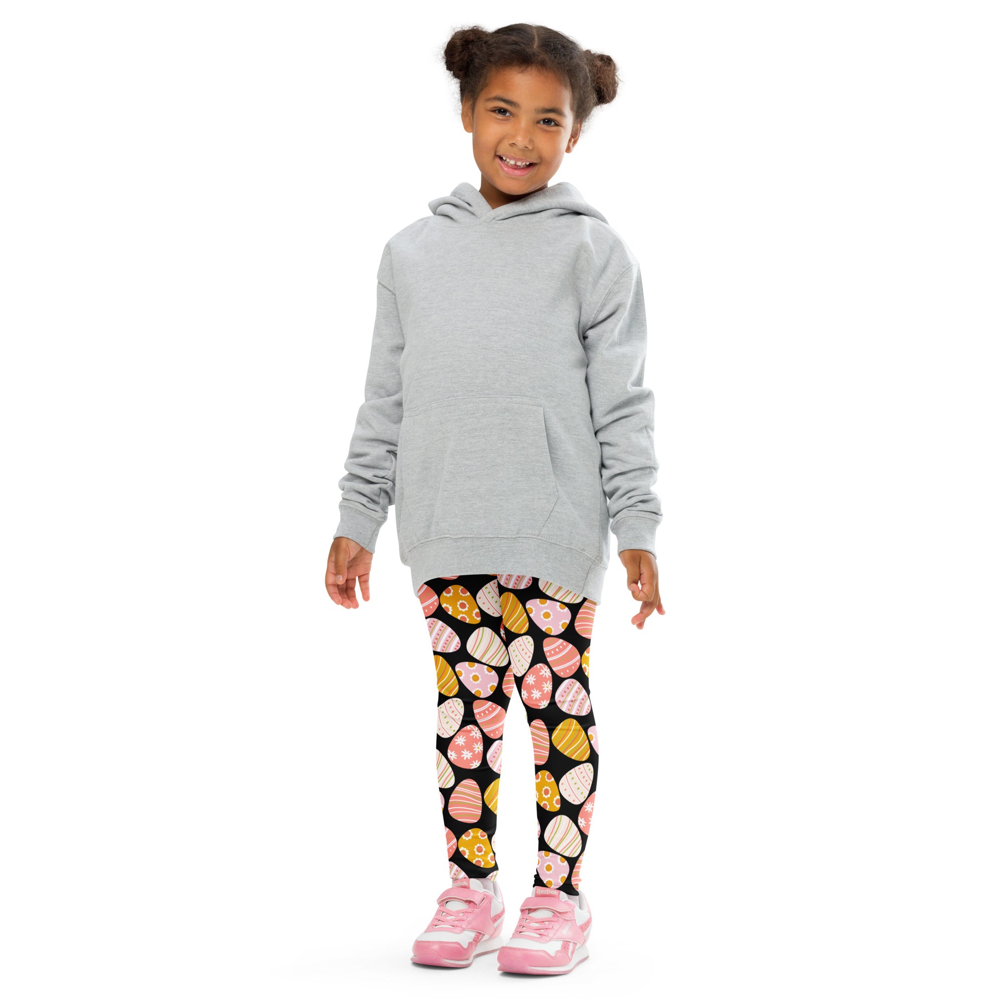 A child wearing girls bold Easter egg buttery soft black leggings with colorful patterned eggs and a light gray hoodie