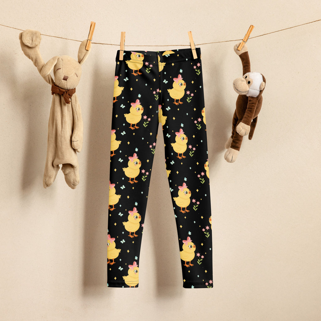 Girls black buttery soft leggings with playful yellow chicks wearing pink hats surrounded by flowers and stars