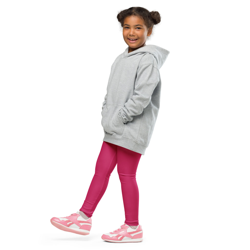 A young girl wearing buttery soft rose red leggings paired with a light gray hooded sweatshirt and pink sneakers