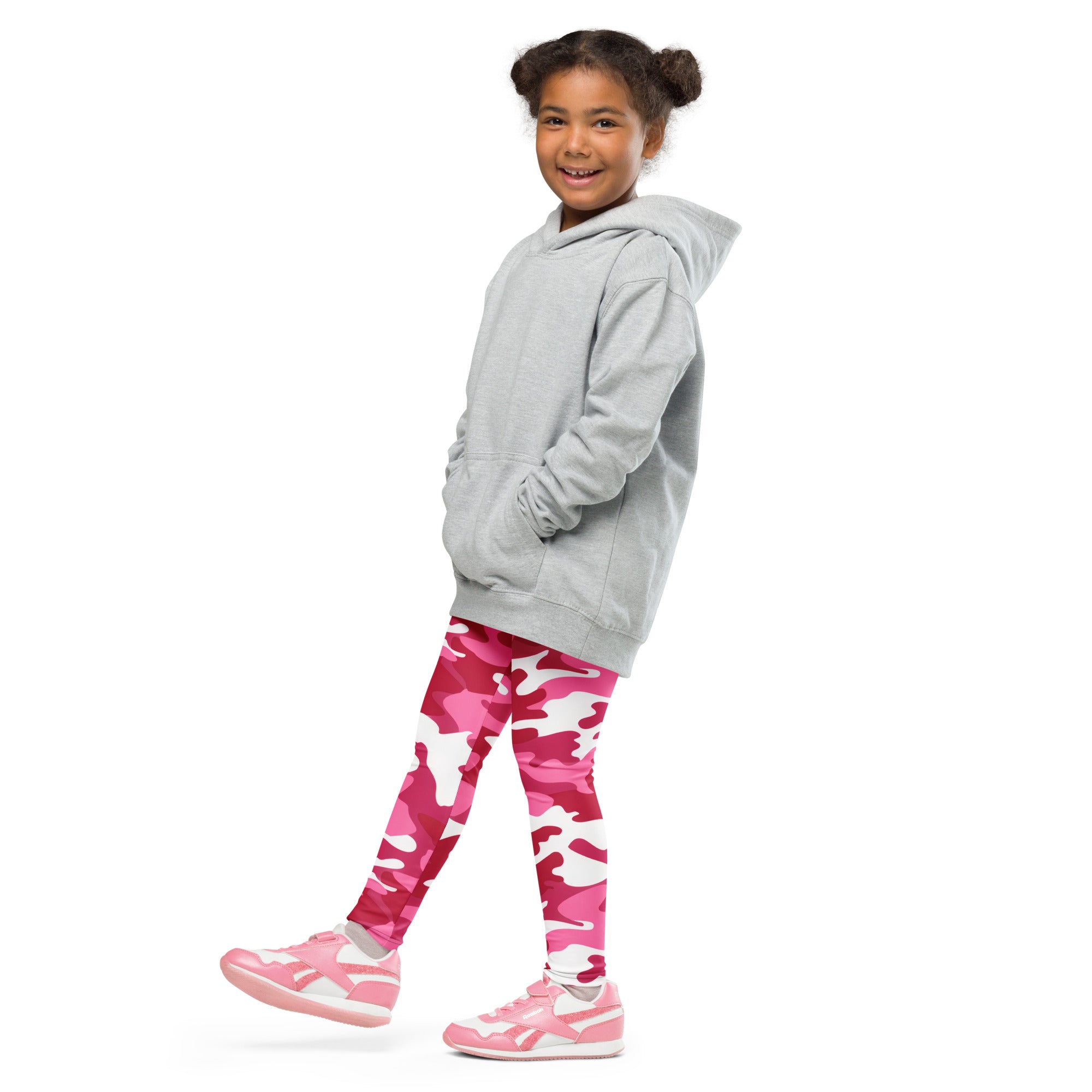A young girl wearing girls pink camouflage buttery soft leggings with light gray hooded sweatshirt and pink sneakers